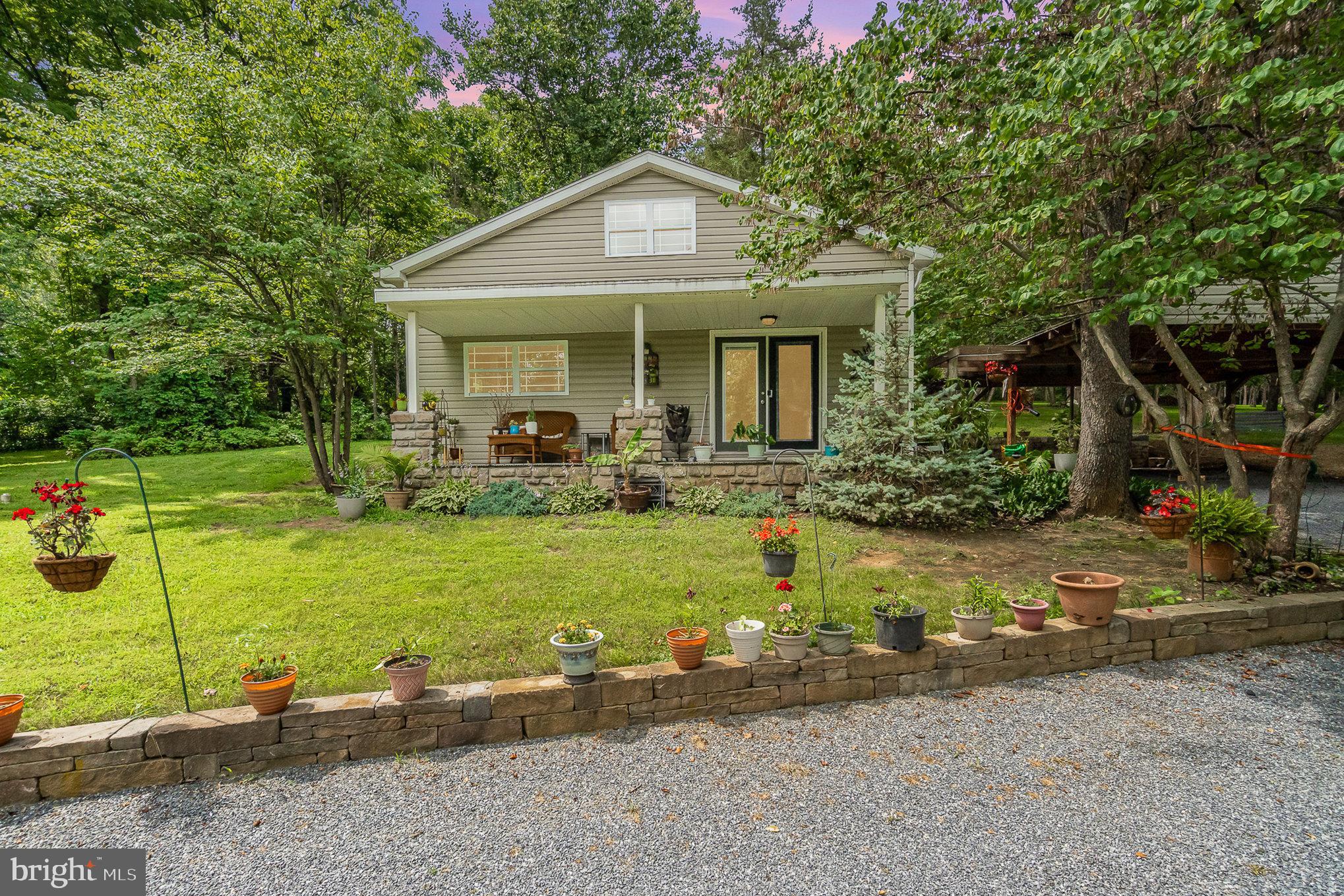 WELCOME HOME! Driving back the tree lined driveway takes you home to a private and tranquil setting on over 10 acres of woods. Sitting on the front porch you have a view that overlooks the pond. Step inside to an open floor plan , where the kitchen dining area opens into the living room. The primary bedroom is on the 1st floor with a full bath and has its own entrance to the patio. The laundry is also on the 1st floor with a 1/2 bath. On the 2nd floor you find another bedroom with its own bath. The lower level offers a tiled floor familyroom with a woodstove and a outside entrance walkup. Outside enjoy the hardscape patio that is tree covered for that perfect shady spot on hot sunny days. There is a 2 car carport and a 30x40 pole building that is perfect for all of your hobbies.