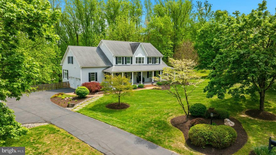 Welcome to this beautifully crafted colonial set on a breathtaking 3-acre lot offering the perfect balance of open, cleared space and mature woods for added privacy. A welcoming wraparound front porch sets the tone, inviting you to relax and enjoy the serene surroundings, while the fenced backyard provides ideal space for outdoor living and play. Step inside to discover hardwood floors throughout the main level, a stunning oak staircase, and intricate molding details that showcase timeless craftsmanship. Glass French doors open to a private study with custom built in bookshelves, perfect for working from home. Formal living and dining rooms provide elegant spaces for entertaining.  The gourmet kitchen, featuring quartz countertops, a large center island, gas cooking, stainless steel appliances, pendant lighting, and recessed lighting—ideal for both everyday living and hosting memorable gatherings. The adjoining family room impresses with a gas fireplace accented by stacked stone, shiplap, and an attractive mantel, while abundant transom windows flood the space with natural light. A charming sunroom offers tranquil views of the private yard and opens directly to the front porch. Upstairs, retreat to the primary suite with a vaulted ceiling, ceiling fan, and expansive walk in closet. The luxurious primary bath features a jetted soaking tub, walk in shower, and double sink vanity. Three additional bedrooms, a full bath, and a convenient laundry room complete the upper level. The finished lower level is an entertainer’s dream, offering a spacious rec room perfect for movie nights, a wet bar with wine fridge, game area, and an additional finished flex room ideal for a gym or guest space. A full bath and walkout access to the backyard add function and convenience. Outside, enjoy a two-car side entry garage, large parking pad, and a spacious deck perfect for relaxing or hosting summer barbecues. The picturesque yard offers flexibility—cleared where you need it and wooded to provide natural beauty and privacy. This exceptional property blends classic elegance, modern comfort, and peaceful outdoor living—truly the perfect place to call home.
