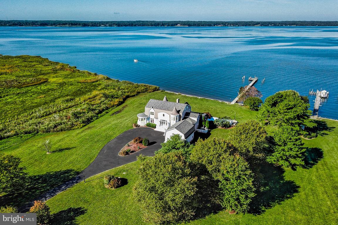 COASTAL CHARM MEETS RELAXED LUXURY. Classic yet informal, mixing contemporary influences with historic aesthetics, this Hamptons styled estate home evokes tradition of elegant and sophisticated design while radiating warmth and coziness. This rare offering of 13+ acres along sandy shoreline of the Patuxent River in historic Calvert County provides impressive sweeping water views visible from every room within the residence. Wide, spacious porches overlook the 44'x18' in ground pool surrounded by level lawn leading to the edge of the water (520'+shoreline) and 6' wide pier equipped to handle multiple power boat/craft dockage just a short boat ride to the quaint seaside town of Solomons Island and to the premier fishing and boating grounds of the Chesapeake Bay. Equestrian pursuits are accommodated with the 5+ stall stable found at the property entrance. The welcoming entry to the residence greets with open foyer and direct views of the river. The expansive living room has 11' ceilings, provides abundant gathering spaces and is anchored by a stone fireplace on one end. River views are accentuated by the large window groupings with French doors leading to the additional 750 sf+ of wide spacious porches (34'x12' and 44'x8') overlooking the pool, lawn and waterfront. The kitchen is at once modern and classic complete with granite counters, ample island, breakfast area and Kitchen Aid appliances. The comfortable dining area with masonry fireplace, also overlooks and opens to the porch, pool and waterfront. A flexible all season great room/game room is tucked to the side. Side entry from the detached oversized 2 car garage leads to a laundry as well as full bath/mudroom. The upper level open balcony hall leads to the master suite with outstanding views, private balcony/deck (12'x16'), sitting area, 17' walk in closet with built ins and private spa mater bath. Three additional sizable bedrooms and two full baths are also located on the upper level. Perfect for year round living or as your coastal retreat. Located 45 miles south of the Capital Beltway, without hassle of hours long drive to DelMarVa locations. An exceptional opportunity !