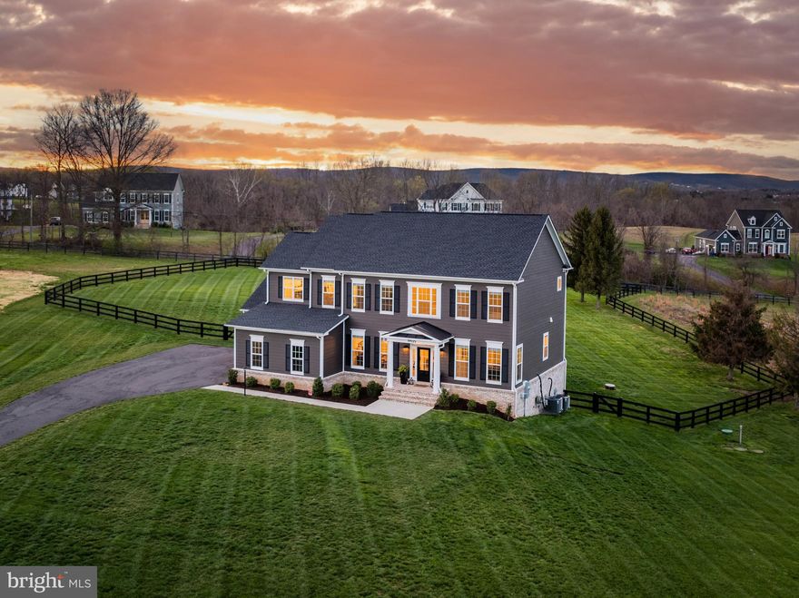 Welcome to this stunning Contemporary Colonial estate, completed in 2022 by Carrington Homes. Nestled at the end of a cul-de-sac on 1.71 acres, this idyllic country retreat offers the best of both worlds: serene privacy and easy access to Purcellville's charming amenities, just a short drive away. Experience luxurious living with no expense spared, including high-end amenities and appliances, two main-level offices, and direct bathroom access from every bedroom for the ultimate in privacy and convenience. The home immediately captivates with its impressive architecture, featuring a double-stall, three-car garage, elegant plantation shutters, and a classically inspired covered entryway. Step inside the double-height foyer, where a sweeping staircase, a front parlor or formal dining area, and two private home offices await. The main level’s upgraded Canadian oak hardwood floors extend into an airy open-concept, achieving a remarkable volume of light and space while maintaining a warm and welcoming feel. In the family room, coffered ceilings add an air of sophistication, and pristine views of your acreage offer the perfect backdrop for gatherings around the fireplace. French doors open to your large main-level deck, extending your living space outside. Enjoy outlooks across the peaceful landscape and fenced yard, as you relax in the sun or dine beneath the stars. The heart of the home is its gourmet kitchen, which appears as if ripped from the pages of a luxury design magazine. Enjoy flexibility for casual meals and entertaining, with a sunny eat-in dining space and breakfast bar island. From the chic countertops, marble backsplash, chef’s hood and stainless farm sink, to the top-of-the-line GE Café appliances, walk-in pantry and upgraded cabinets, every inch showcases a commitment to quality and craftsmanship. Seamlessly transition into the sunroom, a versatile space with open-beamed cathedral ceilings and direct access to the deck. Also off the kitchen is your mudroom with storage and access to the two-car and one-car garages. Near the entry and offices, a powder room with designer wallpaper completes the main level. Upstairs, retreat through double doors to your impressive primary suite, with vaulted ceilings in the bedroom and sitting area, two walk-in closets, and a decadent spa-inspired primary bath featuring a windowed soaking tub and oversized shower. All four bedrooms are thoughtfully placed on the same level, along with the laundry with GE front-loading washer and dryer. An upstairs junior suite sports its own full bath, and two secondary bedrooms share a jack-and-jill bath. Every bedroom features high-end fixtures and blinds, accessibility-minded hardware, and walk-in closets. Finally, comfy carpeting beckons down to the lower level. This sunlit space features full-scale windows and walk-out doors to the yard, creating another naturally bright, finished living area for family and guests. A large recreation room, complete with built-in surround sound system and recessed lighting, opens to the fourth full bathroom, an unfinished room for a potential fifth bedroom or gym, and a huge unfinished area to use as storage, a workshop, or finish to your personal specifications. The basement includes a rough-in for a wet bar addition, and the home includes a hookup for a whole-house generator. Outside, the sprawling, fenced lawn surrounds your deck and outdoor living space, and a propane hookup is ready for an outdoor kitchen. The large paved motorcourt provides ample parking for guests and events. Close to vineyards, farms, and the vibrant small-business community of Purcellville, this estate truly offers the best of both worlds—idyllic country living with easy access to all that Northern Virginia has to offer