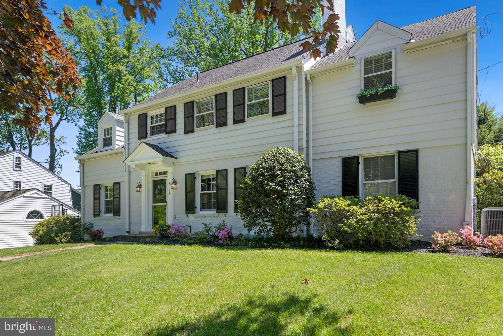 Welcome 5708 Overlea Road, located in the highly sought-after neighborhood of Sumner! Set on a flat quarter of an acre lot, this expanded home features five bedrooms and four full baths and a half bath on the main level. The classic white exterior is highlighted with black shutters and charming window boxes is the ideal combination of space, layout and updates that lead to easy living.
The warm, bright living room is generously sized with a wood-burning fireplace surrounded by built-ins. Off the foyer is the home’s office/library with access to the half bath which could double as a main level bedroom. The flowing floorplan leads you to the entertainers sized dining room and rear family room with walls of windows overlooking the rear garden and access to the large deck. The updated eat-in kitchen is flanked with a generous amount of cabinet space, quartz countertops, stainless appliances, new flooring and a charming breakfast area direct access to the large deck and the amazing, flat backyard, perfect for indoor/outdoor entertaining. The professionally landscaped rear yard and gardens are a true highlight of the home, with a large open grassy area, perfect for a game of catch, and a custom Rainbow playset. Upstairs are four spacious bedrooms and three full baths. Both hall bathrooms have been updated and the rear bedroom is highlighted by a Juliet balcony overlooking the yard. The upper level also has access to the expansive floored attic space via pull-down stairs. The king-sized primary suite features a large dressing room leading to a walk-in closet as well as the primary bathroom with double vanities, a separate soaking tub, glass enclosed shower and heated floors. The finished lower level is complete with a family room space, a separate playroom area, the home’s fifth bedroom, currently being used as an exercise room, the home’s fourth full bath, the laundry room and plenty of storage. A one car garage and driveway parking for two cars round out this beautiful offering. Welcome home!