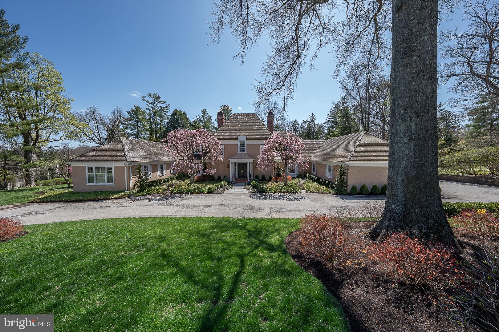 This beautifully balanced French-style home, with only two owners since construction, offers timeless architecture, generous proportions, and light-filled interiors throughout. A gracious two-story foyer leads to expansive formal and informal rooms, including a fireside living room with French doors, a spacious dining room, and a cozy den with fireplace, wet bar, and custom cabinetry.
The sparkling white eat-in kitchen features both island and table seating and opens—along with all main living areas—to a deep covered terrace, ideal for al fresco dining with views of the manicured gardens and oval pool. The main-level primary suite is a private retreat with a bay windowed bedroom, oversized closet, and luxurious bath complete with jetted tub, walk-in shower, and coffee/beverage station. A second large bedroom with full bath, and a sunlit home office with three exposures, complete this level.
Upstairs are four additional bedrooms, three baths, a whimsical hand-painted playroom, and a craft/studio space. The full basement with half bath offers room to expand. Outdoor entertaining is seamless with a pool house featuring a full bath, changing room, and kitchen area. A two-car attached garage connects to a generous mudroom, while a detached garage is perfect for a specialty car or bikes. Two main-level powder rooms and a generator add to the home’s thoughtful amenities.
Refined, comfortable, and beautifully sited—this is French-inspired living at its best.