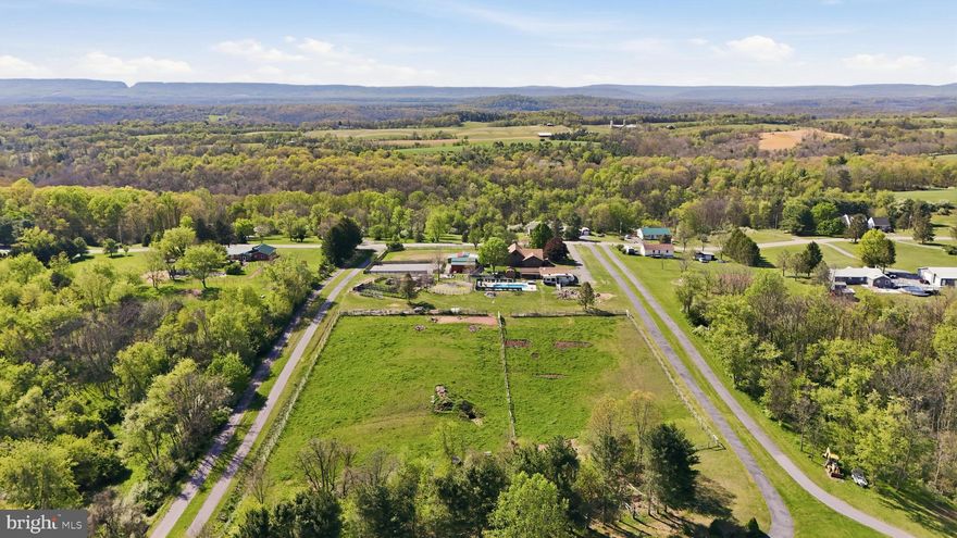 Turn-key horse property meets resort-style living in this fabulous custom-built log home set on over 5 acres of land with mountain views. Spend your mornings in the saddle and your afternoons by the saltwater in-ground pool (installed 2020), all in a setting designed for both everyday function and unforgettable gatherings.

The equestrian facilities are established and in active use. The property features a 90 x 70 riding arena positioned in front of the pole barn, 65’ round pen, a 39’ x 41’ pole barn with electric and water including feed room, tack room and hay storage, plus an additional 4-stall horse barn with electric and water. Property also hosts a chicken coop and duck area, goat pen with shelters, and a fenced area for household pets in the front of the home. In addition, a complete electric fence surrounds most of the property.

The kitchen is the heart of the home with custom cabinetry, stainless steel appliances, and generous counter space for cooking, seating, and entertaining. Enjoy immense storage, slide-out pantry space, and an additional eat-in area, currently styled as an office and coffee bar. Just off the kitchen, you will find a seasonal sunroom/enclosed porch filled with lots of natural light and beautiful views.

The great room delivers the wow factor with cathedral ceilings, exposed rafter beams, and a dramatic wood-burning floor-to-ceiling stone fireplace. Upstairs, the loft-level bedroom, currently used as a game room, overlooks the open and airy great room below.

An oversized primary suite featuring a walk-in closet and a private en-suite with a unique custom-tiled walk-in shower and separate soaking tub. Another main-level bedroom and a second full bath offer flexibility. The second bath features a walk-in shower and convenient dual access from both the kitchen and the second bedroom.

Everyday function is built-in with a main-level laundry room, and the convenience of central vacuum! The lower level offers a finished flex space ideal for a den, playroom, gym, or media lounge, plus over 2,000 sq ft of unfinished storage divided on both sides of the finished area, plus a second washer and dryer. An oversized detached garage adds even more flexibility, with an electric vehicle charger, 50 amp RV hookup, and an attached finished office or work space with high-speed commercial internet. Ideal for hobbies, a studio, or a home-based business.

A rare combination of proven equestrian function and staycation-worthy outdoor living, all in a beautiful mountain-view setting. Schedule your tour today!