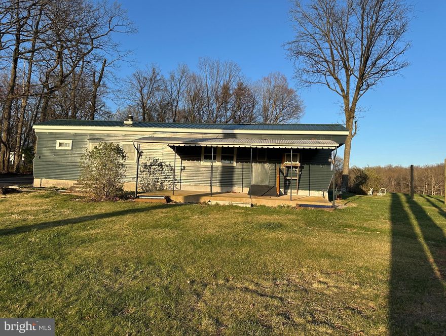Set in a peaceful countryside location, this pre-1976 single-wide mobile home rests on a block foundation and sits on a .46-acre lot. In addition to the home, the property includes a block building with windows—ideal for flexible use such as a workshop, studio, or storage—as well as two additional outbuildings measuring approximately 22x16 and 12x20.
The home itself is in need of repairs and is being sold strictly as-is. The roof is estimated to be about six years old. A front porch offers charming views of the surrounding rural landscape.
If you’re considering alternative uses for the property, please contact the local county offices to inquire about zoning and permitted uses.