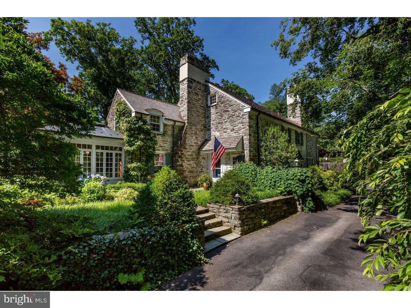 Envision a place to call home that can also act as a getaway, a unique retreat. This 1920s English country estate situated on a private street will do just that. With stunning, secluded gardens surrounding much of the house, it's possible to cherish home and escape the workaday world all at once. The real-stone exterior and new cedar-copper roof perfectly complement the pervasive sense of taking a vacation into serenity created by the circle garden and the sweeping backyard rich with horticultural treasures, 2 flagstone patios, and a freshly refinished pool.  Once inside, the living room beckons: sit in the window seat and gaze at the manicured grounds through the expansive bay window, or admire the room itself with its hardwood floors, crown molding, and stone fireplace. Past the living room is a solarium, the true heart of this home. The solarium features a tile floor with radiant floor heating, a stunning skylight, 2 sets of French doors leading to different gardens, and a wall of windows with window seat and built-in shelves beneath.  The dining room, also enchanting with hardwood floors, leads to the brand new kitchen. Stainless steel appliances, chef's oven and stove, and a Subzero fridge are among the amenities that grace this room, which is adorned with marble counters, Marvin windows, and radiant floor heating. The space is perfect for preparing meals, and the breakfast nook is an ideal place to sit and enjoy them while taking in the landscape. The family room, designed for respite or recreation, is appointed with stone fireplace and built-in shelving.  The 2nd floor offers up an array of rooms. The master bedroom impresses with a picturesque window seat with storage and large linen closet, and the appeal of the master bath?with bidet, sunken tub enclosed by sliding glass doors, large vanity, and skylight  Another bedroom is paired with a private bathroom, a dressing area and closets adding to the allure of this suite. Down the hall are 2 additional bedrooms with generous closet space, a full bathroom, and a washer-dryer set. The 3rd floor, which has new Marvin windows, comprises 2 bedrooms and 2 bathrooms. The fully finished basement is stylish and inviting with tile floors, a fireplace, and a wet bar, making it well equipped for entertaining. There is also a 2-car garage. Additional features of this property includes walking distance to several shopping areas, the train station and in the award-winning Lower Merion school district.