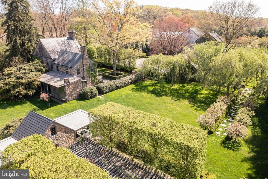 This glorious property with spectacular gardens known as Coltsfoot Farm is situated on 5.6 private acres and is simply breathtaking! It enjoys wonderful privacy and is surrounded by Natural Land Trust property.  As you enter a gated courtyard you’re taken to a world of sublime beauty. Quality materials and focus on meticulous detail can be appreciated by the most discerning. It was the home of artist Charles T. Coiner & his wife May. He was an Impressionist. Many of his paintings arose from the farm fields & backyard scenes of the property. Innovative graphic designer, he collaborated w/ Pablo Picasso, Salvador Dali & Georgia O’Keeffe.  Early origins of the fieldstone house are circa 1754 but the predominant architecture is Federal style. Exterior characteristics of this period are seen in its qualities of understated, elegant proportion. Balance & symmetry and hand cut keystones over the windows provide a sense finesse & refinement. Interior features of the principal residence include antique doors, woodwork & hardware. Spacious open rooms provide a sense of clean lines, yet style & detail have not been overlooked welcoming any period of furnishings. Your eye is drawn to remarkably high ceilings on the first floor.  Handsome wide pine floors throughout with an almost translucent finish catch your immediate attention. The focal point of the kitchen is a large, centrally located marble table for relaxed dining. Soapstone counters provide generous workspace, plus a wall of raised panel built-in cabinetry/closets and a sizeable antique China & storage cupboard create abundant storage. High end appliances include Wolfe, Bosch & Asko. Adjacent to the kitchen is a room designed by George Nakashima, a good friend of the Coiner’s & renowned wood artist of the American Craft Movement. Its Minimalist hallmarks are exposed stone walls, vertical oak paneling, expansive use of glass and cut stone floor. It overlooks an awe-inspiring specimen tree adding to its Japanese influence & captivating views. The home and its ancillary buildings have been beautifully restored. Correra marble & classic hardware appointments provide timeless elements in both the main residence & guest house. A charming stone carriage house w/ covered porch & private patio w/ attached garages is finished w/ quality amenities. The former summer kitchen overlooking a perfectly positioned pergola offers flexible space & versatility w/ its impressive exposed interior walls, cathedral ceiling and is flanked by rooms to either side w/ wrap around walls of glass & radiant heated floors. Surrounded by irrigated vegetable & rose gardens, a marvelous bank barn w/ huge hand-hewn beams is dressed to impress with a wall of espalier flowering pear and affords an opportunity for your own creativity & fancy. Massive steppingstones take you to a grove of dazzling white birches interwoven with perennials leaving you spellbound. There is a fenced area with a charming shed for goats & sheep. There is also a greenhouse adjacent to the barn. As you move through award winning, lovingly planned flora there is a seamless distinctive blend of simpatico. This extraordinary property garnered a coveted spot and was recently featured in the Private Gardens of Philadelphia, being one of the finest in its Bucks County selection. This well-planned habitat provides a panoply of changing colors & textures as we move through the seasons. Walkways and pleasant landscapes serenely complement each other and provide a place for reflection. Pleasing entertainment areas create a place to celebrate life with family & friends. Coltsfoot Farm offers a rare opportunity & a feast for the eyes! Its current owners have been exceptional stewards. Enjoy its incomparable allure!