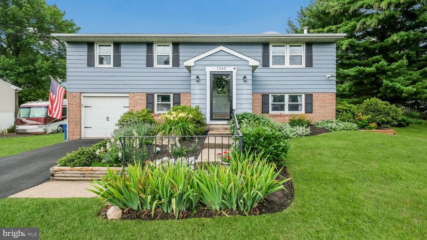 Situated on nearly a half-acre lot along a quiet tree lined street just moments from downtown Perkasie, this beautifully updated four-bedroom bi-level home offers an impressive blend of modern amenities and spacious living. You are welcomed by a covered, enclosed portico style entry which leads into the home where a split staircase guides you up to the main living area or down to the lower level. Upstairs, an open-concept layout seamlessly connects the living room, dining room, and spacious kitchen, creating a bright and inviting space perfect for entertaining. A bump out sunlit garden window in the dining room and an oversized double window in the kitchen fill the rooms with natural light. Luxury vinyl plank flooring has been installed throughout the kitchen, living and dining areas, hallway, hall bath, and primary bedroom. Three comfortable bedrooms are located on the main level, including a remodeled primary bath with a barn door, glass shower, subway tile, and an updated hall bath with stylish vanities and modern finishes providing both functionality and charm. The kitchen is equipped with a full set of modern stainless steel appliances, peninsula island seating and recessed lighting. Downstairs, you’ll find an expansive recreation room featuring built-in shelving, storage, and a cozy wood stove. This inviting space opens to a bright vaulted sunroom with durable flooring and picturesque views of the backyard, perfect for enjoying the outdoors year round.  A versatile fourth bedroom option, currently used as an office, along with a half bath with updated flooring and vanity, provides flexible living space. The lower level also features new carpet in the office and family room, a laundry and utility/mudroom, and direct access to the attached garage with a “smart” Wi-Fi enabled opener. Other notables include two cast iron stoves, one a high efficiency wood stove model with a stainless steel chimney, providing warmth and serving as attractive focal points in both the living and family rooms. A 4-zone mini-split heating and cooling system for year-round comfort, and new windows on the upper level. The entire water system has been thoughtfully improved with a complete well mechanism replacement, a new bladder tank, and a whole-house filtration system featuring an iron tank, softener, micron filter, and UV light. Public sewer. A new water heater. Modern flooring in the sunroom, and fresh finishes throughout further enhance this move-in ready home. Outdoors, the property offers a spacious backyard ideal for both recreation and relaxation, complete with a fire pit area, swing set, and storage shed.  You'll also find a thriving organic garden with a local following. Its fresh produce is even sold at the owner's charming farm stand. This meticulously updated home combines style, comfort, and functionality ready to welcome you home!