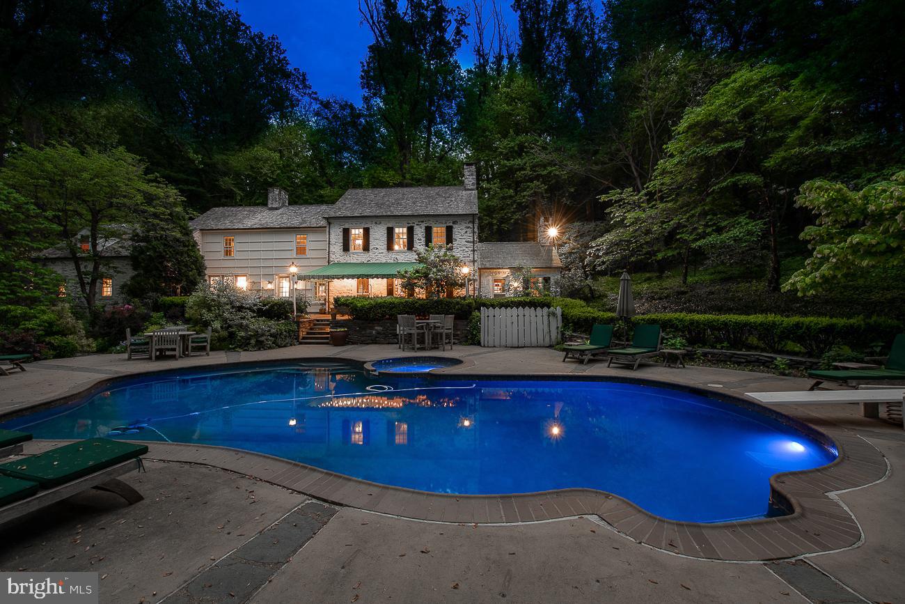 This truly classic Walter Durham Main Line colonial set upon 3.46 lush acres of privacy yet minutes to the Village of Gladwyne and downtown Ardmore exudes the classic Main Line lifestyle. As you walk up the stone path and enter the front door you immediately see the views of the rear grounds with a beautiful pool and spa overlooking lush trees and personally designed English gardens. The formal living room with an abundance of built-in cabinetry and original moldings makes a wonderful room to entertain with its built-in bar discreetly tucked behind cabinetry and its classic stone fireplace. The spacious dining room is conveniently located off the kitchen through an arched doorway and features a grand fireplace surrounded by original built-ins and has a Dutch door leading out to the rear flagstone patio. A cozy family room provides a wonderful place to spend time with family or can be used as a separate playroom. The bright eat-in kitchen boasts Rutt cabinetry with granite counters, farmhouse sink, a new Bosch dishwasher, new Subzero refrigerator, and new wine cooler, double ovens, and gas cooktop plus back staircase. The sliding door provides a plethora of light and makes access to the rear patio and pool convenient for grilling and outdoor entertaining. Tucked just off the mudroom in its own space, is the 4th bedroom and full bath perfect for guests plus a separate office/bonus space. On the second level find the gracious primary suite surrounded by windows on three walls with a fireplace and offers views overlooking the rear grounds. The adjacent primary bath has a walk-in shower and concrete counters evoking a warm rustic farmhouse feel. Off the primary bath is a room currently being used as a closet surrounded by custom enclosed cabinets but could also be used as a 5th bedroom/office/bonus space. The second floor also houses Bedrooms 2 & 3 which are also bright and spacious and offer adequate closet space and their own baths. A walk-up third floor is unfinished but could easily be finished if additional living space was desired. Complete with a two-car garage providing inside access and a long driveway with lots of parking space. Outside is truly an oasis-you will never want to leave with the heated pool and spa, flagstone patio with awning for dining al fresco, quaint storage shed, garden pathways, and gates punctuated with perennial gardens and an array of blooming trees and extensive landscape lighting. Wired for sound in the primary bedroom, dining room and family room. Built in a bygone era where craftsmanship and longevity were the goals this is a truly special estate in a magnificent Lower Merion location.
