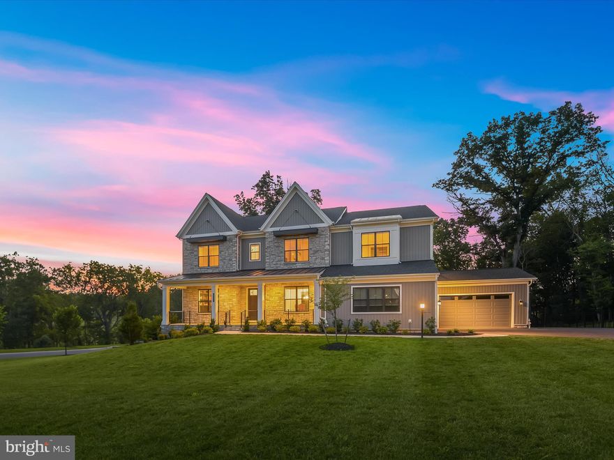 Introducing a stunning luxury residence, Parkhurst-Modern Farmhouse model crafted by Toll Brothers in 2022, where elegance, comfort, and craftsmanship converge across more than 8,000 square feet of exceptional living space. Situated on a corner lot backing to trees, this stone-accented estate rests on nearly an acre, offering privacy, sophistication, and unrivaled attention to detail. Every inch of the home has been thoughtfully upgraded, featuring high-end finishes, designer fixtures, and elevated materials throughout. From the moment you arrive, the home makes a bold impression with its stately architecture and flagstone-covered front porch. Inside, the foyer opens to a dedicated home office on the left, outfitted with rich, wraparound built-in bookcases and French doors for privacy. To the right, the formal dining room awaits, perfect for hosting guests beneath elegant, design-inspired lighting. Straight ahead, the soaring great room steals the spotlight with its dramatic two-story ceiling, striking wood beams, sleek linear fireplace, and a modern multi-panel stacking door crowned by clerestory windows that bathe the space in natural light and expand the living space.
Just beyond the sliding glass doors, a screened deck extends your living space outdoors. Designed for all-season enjoyment, this luxurious retreat features a remote-operated screen and a beautiful stone-accented gas fireplace creating a seamless transition from indoor to outdoor entertaining. Back inside, the gourmet kitchen is a chef’s dream. It boasts stacked soft-close cabinetry in a rich, custom tone, an expansive island with a stunning waterfall granite countertop, and a full-height granite backsplash that ties the space together. Top-of-the-line stainless steel appliances include a six-burner double gas range, dual dishwashers, wall oven, apron sink, and more, all part of the premium Chef’s Kitchen package. A light-filled breakfast room overlooks the backyard through a picture window, while a spacious walk-in pantry, powder room, and mudroom with drop zone and access to the 4-car garage with electric vehicle chargers provide everyday functionality with elevated style. This level also includes a private bedroom suite with its own bathroom and laundry room, along with a separate living area featuring a wet bar and beverage refrigerator, perfect for guests, in-laws, or multi-generational living.
Upstairs, the luxurious primary suite welcomes you with a built-in wet bar and beverage refrigerator, ideal for creating a private morning coffee bar. To the right is a spacious bedroom accented with crown molding. Down the hall are two custom walk-in closets and a lavish primary bath with dual vanities, a freestanding soaking tub framed by a picture window, and a spa-like shower with floor-to-ceiling tile and a frameless glass door. Three additional bedrooms each offer walk-in closets and private en-suite baths with upscale finishes. The upper-level laundry room is expansive, featuring generous counter space, cabinetry, and a sink.
Descending the upgraded hardwood staircase with iron balusters, the lower level reveals a media room that conveys with high-end equipment, a sprawling recreation area with walkout access to the backyard, and a full guest suite with its own sitting room and full bath. This level also includes a third laundry room and a large storage space.
Outside, enjoy a flagstone-covered patio, fenced backyard, and plenty of space for gatherings or quiet moments in nature. The four-car garage includes an electric vehicle charging outlet, and the home is prepped with a rough-in for a whole-house generator, adding convenience and peace of mind.
This extraordinary property redefines luxury living with thoughtful design, fully customized upgrades, and an effortless blend of beauty and function inside and out.