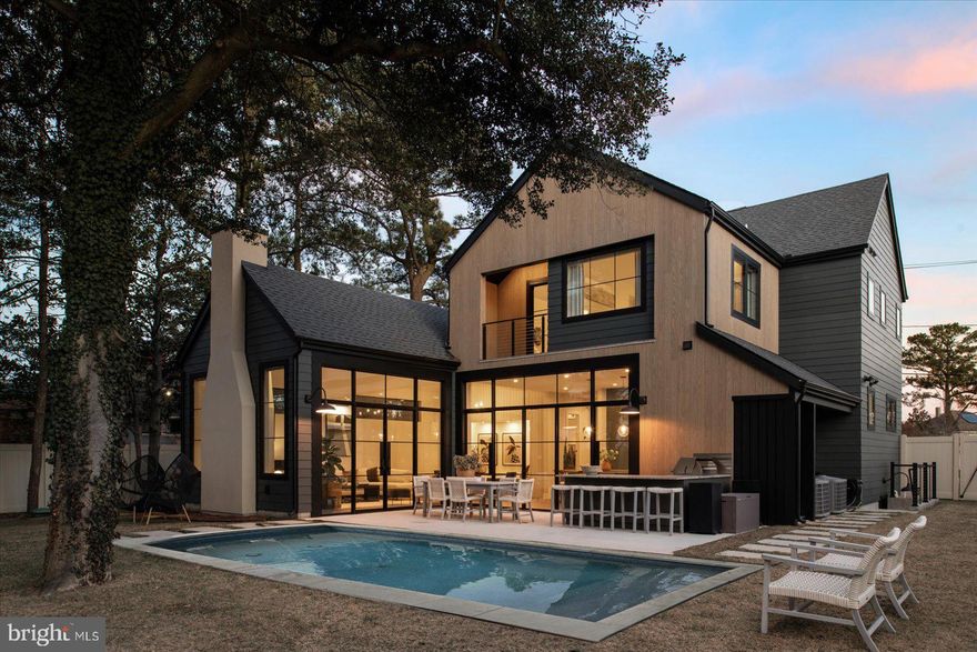 Exquisite modern luxury awaits in downtown Rehoboth Beach. Just blocks from ocean beaches and steps from local dining and shopping. This well-designed, spacious five-bedroom custom home serves stunning interior vignettes and embraces the outdoors with huge, black-framed casement windows. Just two years young, and situated on an oversized lot, this sleek home is meticulously designed for functionality and filled with an abundance of natural light. Facing southeast, the spacious foyer, second floor loft and all five bedrooms are flooded with beautiful sunlight all day long. Engage with the community on your front porch, or retreat to your private garden oasis and experience sunsets in the inground, heated saltwater pool. The open kitchen and large living area benefit from western exposure and are bathed in elegant warmth each evening at magic hour. Host dinner parties in your spacious kitchen/dining room, or outdoor poolside kitchen patio. The professional stainless ZLine seven burner gas range with griddle plate and polished brass detailing is the chef's kiss! And the oversized quartz island will keep you holding court as you prepare any meal. The custom kale green lacquer cabinetry is adorned with antiqued brass hardware, adding a vintage character to the contemporary space. Fisher & Paykel 36" refrigerator, luxe double drawer dishwasher and drawer microwave are all integrated not to detract from clean modern lines. The gracious living room with a central fireplace has dramatic vaulted ceilings and a wall of glass overlooking the backyard oasis. Three of the five bedrooms offer ensuite baths, all with walk-in showers and one with a free-standing soaking tub. Two of the ensuite bedrooms are on the main floor, off the spacious entry foyer/wet bar area.  Tasteful high-end finishes, such as marble tile, quartz vanities and walnut slab stair treads nod to quiet luxury.  A second floor sitting area is perfect for movie night, and access to the second-floor covered porch offers views of the pool and garden. Two laundry areas, equipped with both Electrolux and Miele washers and dryers will keep your beach, and pool towels ready for your next dip. Use the extra Smeg fridge to chill beverages, and the overflow freezer for the ice cream cake!  Come experience this gem of a home for yourself. Stroll through the open floor plan and explore each suite. Live beautifully, live easily, live happily at 63 Lake Avenue in the heart of downtown Rehoboth Beach!