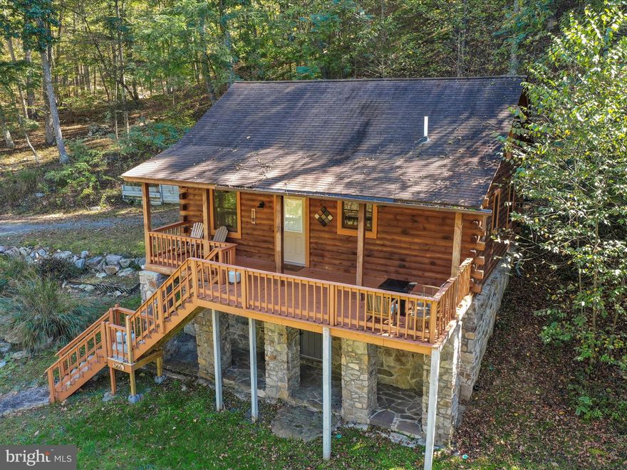 Rustic Charm & River Lifestyle – Log Home on 2 Wooded Acres - Used as an Airbnb -
Country living at its best! This 2006 log home with natural stonework sits on 2 partly wooded acres and offers the perfect blend of rustic charm and modern comfort. The open living room features soaring wood ceilings and hardwood floors, creating a warm, welcoming space to relax and unwind.  Step onto the covered front porch and watch the wildlife go by.
The updated kitchen features stainless steel appliances, a newer double sink, and faucet. Main floor bedroom and full bath with washer/dryer add everyday convenience. Relax in the hot tub after a day of hiking, kayaking, or fishing.
Used successfully as an Airbnb with a strong rental history, this home features multiple mini splits for efficient heating/cooling, fiber for internet and two driveways—upper driveway provides easy access. Best of all, enjoy access to a private common area on the scenic Cacapon River—perfect for swimming, tubing, and unwinding.
Whether you're looking for a peaceful full-time residence or a weekend escape, this property offers the lifestyle you've been dreaming of.