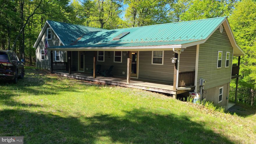 Spacious moutain retreat for the whole family to enjoy! This cabin will surely accommodate your family gatherings with plenty of room to sleep, play and relax as you immerse yourself in this mountain oasis.  Large kitchen with all the conveniences of home. Breakfast bar for extra seating or for enjoying that morning coffee or a snack. The original 1 bed, 1 bath cabin with loft and Living area w/ beautiful brick wood burning FP, was built in 1994. The addition was added in 2006, which included 3 more spacious Bedrooms, Foyer/Den area, Dining area with Propane FP, Mud Rm (or Pantry). Primary Bedrooms both upstairs and downstairs  have walk-in-closets. Upstairs Primary has an ensuite and direct access through the French doors to the full length back deck.  The fully finished basement, in addition to the 2 bedrooms has a large cozy Living area with wood burning stove. French doors lead out to the concrete patio and workshop/storage area.  The cabin's water source is a Cistern which has served this family well throughout the years.  This is not an HOA, but some covenants & restrictions do apply. Development is behind a locked gate.