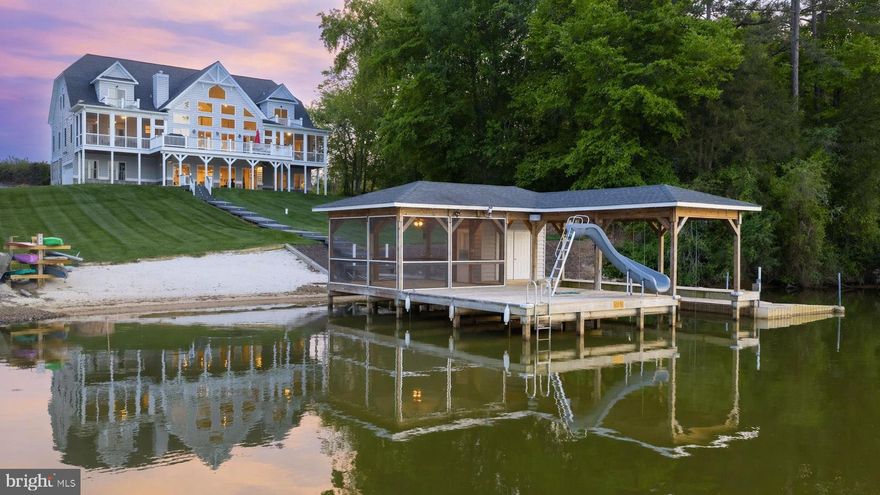 Welcome to resort-style living on the public side of Lake Anna, where long sunny days, sparkling water, and unforgettable sunsets become your everyday backdrop. Built in 2019 and set on just over an acre in the desirable Summerview Point community (with no HOA), this stunning Craftsman-style waterfront home offers over 7,000 square feet of beautifully finished space designed for both relaxation and entertaining—and is being sold fully furnished with an acceptable offer, making it truly turn-key! With 150 feet of pristine shoreline, the setting delivers the ultimate lakefront experience from every angle. From the moment you walk in, you’re greeted by soaring ceilings, a wall of glass framing the lake, and water views from nearly every room. The open floor plan allows the kitchen, family room, and dining areas to flow effortlessly together, creating the perfect setting for gatherings. The gourmet kitchen features a massive center island, granite countertops, and stainless steel appliances—ideal for hosting after a day on the water. The main-level primary suite features a beautifully appointed bath, walk-in closets, and private access to a screened porch overlooking the lake. Upstairs, two spacious bedroom suites each enjoy their own private balconies and baths, creating a peaceful escape for guests. The walkout lower level is built for entertaining, complete with a full kitchen, expansive recreation and dining areas, two additional bedrooms, a full bath, and plenty of space to unwind. Step outside and the lifestyle truly comes alive—composite decking, multiple screened porches, balconies, and patios all designed to take in the breathtaking views and fresh lake air. Down at the water’s edge, you’ll find everything you could want for the ultimate lake experience: a deep water covered boathouse with electric lift, sun deck with slide, triple jet ski pad, storage room, and a huge sandy beach perfect for lounging or playing by the water. Gather around the lakeside fire pit as the sun sets, or spend your days cruising, swimming, and soaking it all in. 2-car garage, paved driveway and lake-fed irrigation. Located less than 2 hours from Washington, D.C., this home is perfect for even a quick weekend trip. Enjoy close proximity to local dining and favorites like Tim’s at Lake Anna, Moo-Thru for ice cream and mini golf, The Cove restaurant, and nearby marinas. With high-speed FiberLync internet and short-term rental potential offering strong income opportunities, this property delivers not just a home—but a lifestyle of lakefront luxury, fun, and lasting memories.