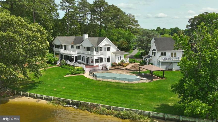 Welcome to your dream waterfront retreat! Situated on a beautifully landscaped 1.4-acre lot, this expansive 6-bedroom, 6.5-bath home boasts over 5,100 square feet of thoughtfully designed living space that blends luxury, comfort, and functionality.  A circular asphalt driveway welcomes you to this exceptional property featuring a detached 2-car garage with a private apartment above—ideal for guests, in-laws, or rental income. Inside the main home, you're greeted by solid mahogany hardwood floors and an open-concept layout that effortlessly connects the heart of the home to the outdoors.  The spacious kitchen is a chef’s dream with a large eat-up bar, pantry, and high-end appliances, opening into an all-glass main-level living area offering breathtaking water views.  Designed for gatherings and multi-generational living, the home includes a first-floor owner's suite with a spacious steam walk-in shower, private access to the screened porch, expansive deck area, and serene water vistas. Two additional en-suite bedrooms on the main level, along with a cozy office with water views, laundry room, and a fully equipped gym, add to the home’s thoughtful layout.  The formal dining room, complete with a wood-burning fireplace, overlooks the water, creating the perfect backdrop for memorable meals. Upstairs, you'll find a spacious game room, second laundry, three additional en-suite bedrooms, including a second owner's suite with access to the expansive balcony—perfect for morning coffee or sunset views.  Step outside to enjoy a true outdoor oasis that includes a waterfront pool,  expansive hardscaped patio, and a large playful backyard.  For the water enthusiast, the property features a bulkhead dock, boat lift, small beach entrance ideal for kayaking, and easy water access.  From the mature landscaping to the thoughtful layout and finishes, every detail has been considered in this one-of-a-kind home that blends gracious living, marvelous water views, large waterfront back yard with unmatched recreational opportunities.  Don't miss your chance to own a rare waterfront gem that's perfect for year-round living or a weekend escape.