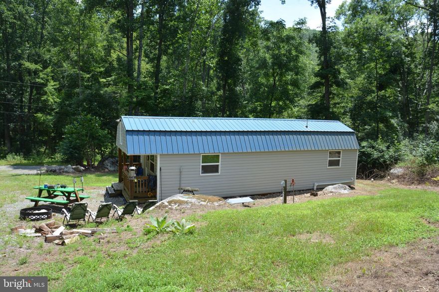 Quite an interesting property that will no doubt draw interest.  This is a 5 acre lot that has over 250' frontage on Dillons Run, a state recognized trout stream.  Well and septic has been installed and there is a 12 x 40 converted shed, metal roof, new vinyl siding, with a completely finished out interior (pine walls, ceiling). Bedroom, full bath, kitchen (refrigerator/stove/microwave), spacious living room.  Carpeted.  Pull down stairs takes you to a loft area that is carpeted and has a mattress.  Both main level and loft area have separate mini-split units for heat and air.  The furnishings will convey with the sale.  A rear shed has a water softening system and elaborate filtering system.  The phone line offers DSL for Internet.  Think weekend use now.  Build your permanent home in the future.  A camper is also on a separate pad site that can be purchased.  This 1600 acre community offers a swimming lake with a beach/playground/picnic pavilion, tennis court, a stocked fishing lake and ability to drive your ATVs on the gravel roads. Not much traffic back here as the road deadends a short distance down.  Not an HOA, but a committee collects annual maintenance dues of $400.  This is a rare opportunity to purchase something on the creek.