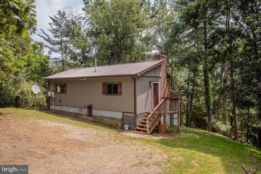 Charming cabin in peaceful, wooded setting offers the perfect weekend get-away or full-time residence.  This cabin offers an open concept living room, and eat-in kitchen area, with sliding door to a large back deck.  There are two well-sized bedrooms, a full bathroom with tub/shower combo plus a laundry nook with front loading washer and dryer included.  Installed solar system hooked into the electric meter helps reduce usage costs.  There are 2.5 acres to enjoy and explore, plus yard space to enjoy a bonfire pit and parking for 2-3 cars comfortably.  This rustic yet comfortable cabin has an efficient heat pump and central AC and a fireplace with wood burning stove insert.  This would make a perfect short-term rental property as well.  Don't miss out on this opportunity to get back to nature!