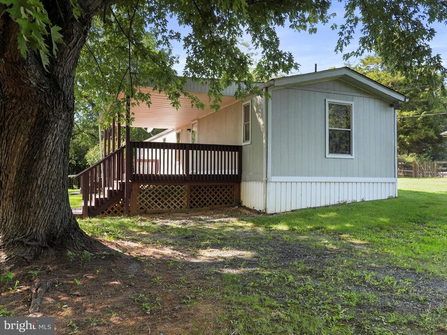 Very nicely maintained affordable manufactured home on almost 1/2 acre lot.  Everything about this home has been maintained very well over the years and is move in ready.  The kitchen features main fridge and secondary "wine" fridge, but could be replaced with a dishwasher very easily.  Nice large covered deck greets you at the main door and covered rear porch takes you to a large open play area.  Well house is in the back yard in the secure brick building.   There is a nicely fenced area out back as well.  Home is set on poured pilings, but does not have a "permanent foundation or block foundation."