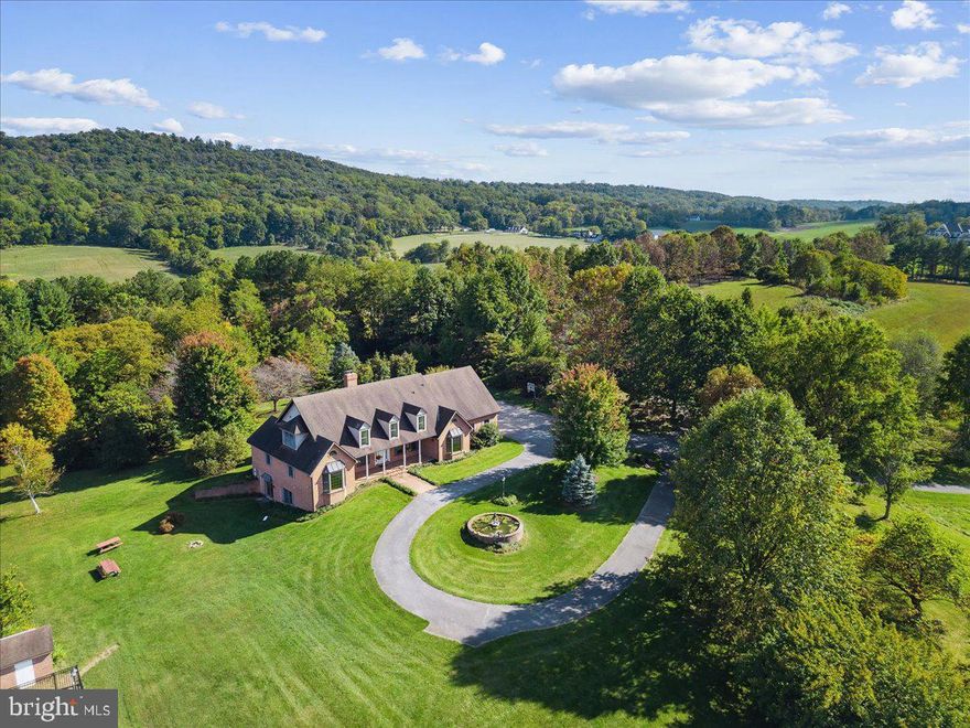 Welcome to your dream retreat nestled on 26 acres of pristine farmland near the base of Sugarloaf Mountain. Situated on a dead-end road, the property feels private and secluded but is only 40 miles from Washington DC. From the moment you arrive, you'll be captivated by the very rare opportunity this extraordinarily beautiful property provides. The expansive custom-built brick home is the epitome of solid craftsmanship —with high ceilings, custom woodwork, oversized light-soaked rooms, and stunning vistas. The entire interior has been newly painted and is move-in ready. Designed for single-floor living if desired, the main floor boasts hardwood floors throughout, and 2 separate owner's suites, each with large bedroom, en-suite bathroom, and separate entrance. At the center of the main floor is a large family/living room with a wood-burning fireplace and a beamed cathedral ceiling, creating an atmosphere both cozy and elegant. Off the family room is the large country kitchen, featuring custom solid walnut cabinets hand-crafted from trees on the property. Enjoy your coffee and meals in the dining nook surrounded by windows overlooking the backyard. The formal dining space features double crown molding and offers a beautiful setting for special occasions and family gatherings. The main floor also boasts a large office, with floor-to-ceiling solid walnut cabinets and wainscoting, all custom crafted from trees on the property. The office is perfect for remote work, with high speed internet service available from local providers or Starlink. Off the kitchen is a half-bath for guests, and convenience is key with a large main-level laundry room that includes a washer, dryer, sink, and additional cabinets for organization and storage. A stunning, sunroom, with custom cherry woodwork, tile floor, and panoramic windows invitesi the outdoors in and provides a serene space to relax and enjoy the beauty of the surrounding landscape. Off the sunroom and running along the back of the house is an expansive patio, great for barbecues, bird-watching, sunning, and relaxing. Upstairs, the second level boasts new carpeting and two additional bedrooms — each with its own bathroom — and a large bonus room ideal for a variety of uses, whether as an additional bedroom, playroom, media room, or hobby space. Walk-in attic space provides abundant storage throughout the second floor. The lower-level finished basement is an enormous 2488 square feet, consisting primarily of one gigantic room suitable for in-home business, playroom, meeting room, or retreat. The basement also boasts an office and full bathroom which could possibly be used as an in-law suite one day, as well as a gas log stove for additional warmth in the winter. Walkout double doors provide easy access to the expansive yard. The two-car attached garage offers secure storage for your vehicles. The property boasts a large private gated pool; a level and protected recreation area large enough for a tennis or pickleball court; a storage shed; a pergola covered with wisteria; and an old chicken house. Over the past four decades, the owners planted thousands of trees including specimen evergreens, oak, walnut, cherry, maple, hickory, redbud, dogwood, persimmon, fruit trees, and many others, so that the property today is a mix of forest, park-like landscaping, and rolling open fields. Privacy is paramount on this sprawling 26-acre estate, allowing you to escape the hustle and bustle of daily life and experience the serenity of country living. Yet it is in the highly-rated Urbana School district, and if you are interested in commuting to downtown DC, the MARC commuter train at Dickerson is only 8 minutes away with service to Union Station. Beautiful downtown Frederick is only 20 minutes by car, and for the outdoor set, the property is close to hiking trails and recreation on Sugarloaf Mountain, hiking and biking on the C&O Canal, and numerous historical sites.