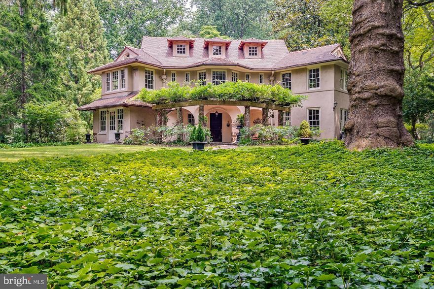 Welcome to 1 Porter Lane, in leafy Rose Valley. Built in 1912 by revered architect William Lightfoot
Price, this three story dwelling is known as the Butterfly House for the symmetrical angled wings
flanking its center. Set on nearly one acre, this landmark home has been occupied by generations of one
family for the past 56 years. Tucked away on a charming cul-de-sac, the house sits among an secluded enclave of five homes of complementary design. All date back to the early 1900s and have been meticulously maintained since. From the front yard, a main brick pathway leads to a pergola whose ancient wisteria vines bloom each spring, and later shade the spacious front porch. This path matches the brick-red Mercer tiles on the roof. Inside, original hardwood and heart pine flooring feature largely in the home. The house is cooled by central air conditioning. On the left of the spacious entry hall, the first floor boasts a large living room with a fireplace and builtin cabinetry as well as a small parlor. To the right is a long dining room that can accommodate all your holiday guests. A charming touch is the run of original casement windows across the front of each of the two main rooms.Adjacent to the kitchen is a breakfast room and butler’s pantry equipped with sink and wine refrigerator. This room includes a door to the side yard and a small terrace. A den with a full bath also has access to a rear porch. A back staircase from the kitchen leads to the second floor.The second floor is primarily accessed by a grand curving staircase from the front hall, which retains its original finish.
On the second floor are five bedrooms and one full bath. The bathroom features original cobalt subway
tiles halfway up the wall, while the floor matches with small blue tiles.The spacious primary bedroom boasts a fireplace, a walk-out terrace, a seating/dressing area, and windows on three sides.
One of the bedrooms features a bay window, and several contain large closets.
A study on the second floor is handsomely finished with built in shelves, a working fireplace, casements,
and double hung windows.The third floor houses two bedrooms and a third full bathroom. In one bedroom, a door opens to an outdoor porch with stunning views of the gardens and woods. Another room presents options for a home office or hobby room. A staircase provides access to the basemen laundry room and a 2-car garage.
A more recent addition to the property is a charming greenhouse featuring gravel flooring on the sides
and a brick walkway down the center. With ample tables on either side for potting, a radiator keeps
plants and planters warm in the early gardening season. Open the door at the end of the greenhouse
and step into a tool shed, which also has a brick floor.
Facing the front of the house, note the large driveway on the left. With a grand original wrought iron
gate, this provides ample spaces for family members and guests to park. Ultimately, the driveway leads
to original under-house parking spots.
1 Porter Lane is within easy walking distance to the Rose Valley-Moylan train station, 
Hedgerow Theatre, Rose Valley Swim and Tennis Club, Rose Valley Historical Society, the Old Mill, and woodsy trails. Just beyond the train station is the town of Media, with an abundance of shops and restaurants. Access to the Blue Route is a short drive away, leading to I-95 to the east and the Schuylkill Expressway to the west. Many of the historic homes in Rose Valley - including the others on Porter Lane - were inspired by the English Arts and Crafts Movement. William Price’s use of reinforced concrete and decorative Mercertiles in the design of the Butterfly House, as well as hotels and railroad stations from the East Coast to the Midwest, was far ahead of its time, proving his conviction that buildings should be beautiful as well as useful.