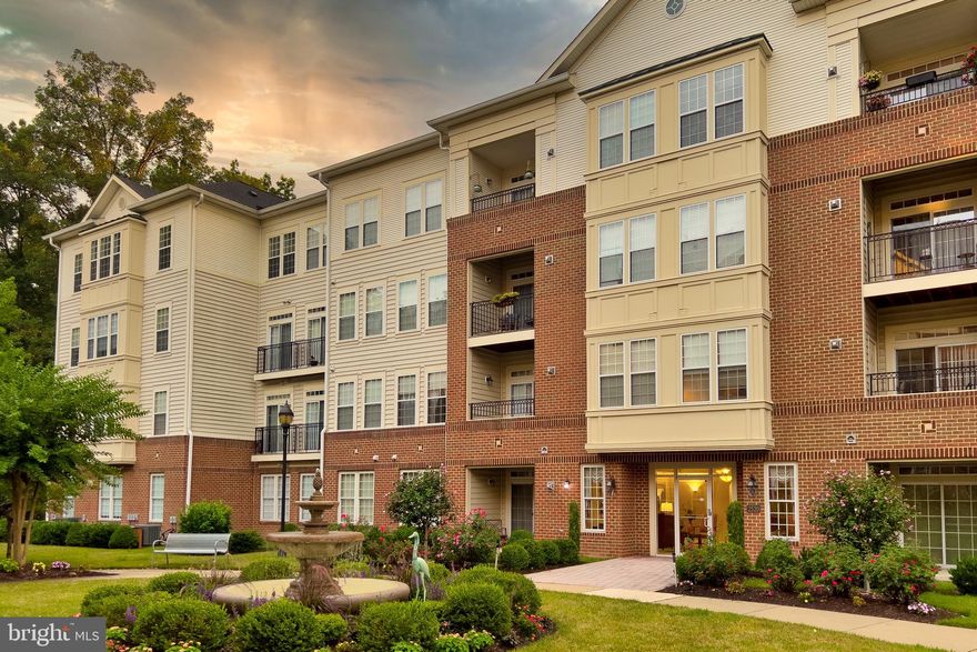 Easy & carefree living in this sought after 55+ Ellicott Hills community.  Unit 406 is situated on the TOP floor in the back corner of this elevator building which provides for lots of natural light (windows on 2 sides)! Fantastic layout offers a proper foyer; 2 bedrooms & 2 baths on opposite ends of the unit; a formal dining room; generously sized living room; an eat in island kitchen; a den opening to the kitchen with custom built ins; your own relaxing covered balcony overlooking trees & nature; full sized washer/dryer. The unit has just been freshly painted, brand new carpeting installed and Quartz counters just added in the kitchen. Parking is a breeze with your own, in building garage space + there is plenty of other parking too! Stop worrying about yard work & outside maintenance - start socializing with neighbors & friends in the beautiful courtyard, the building lobby & at the stunning community clubhouse complete with a large fitness room, library, game room, gathering spaces, a pool, tennis, & more!