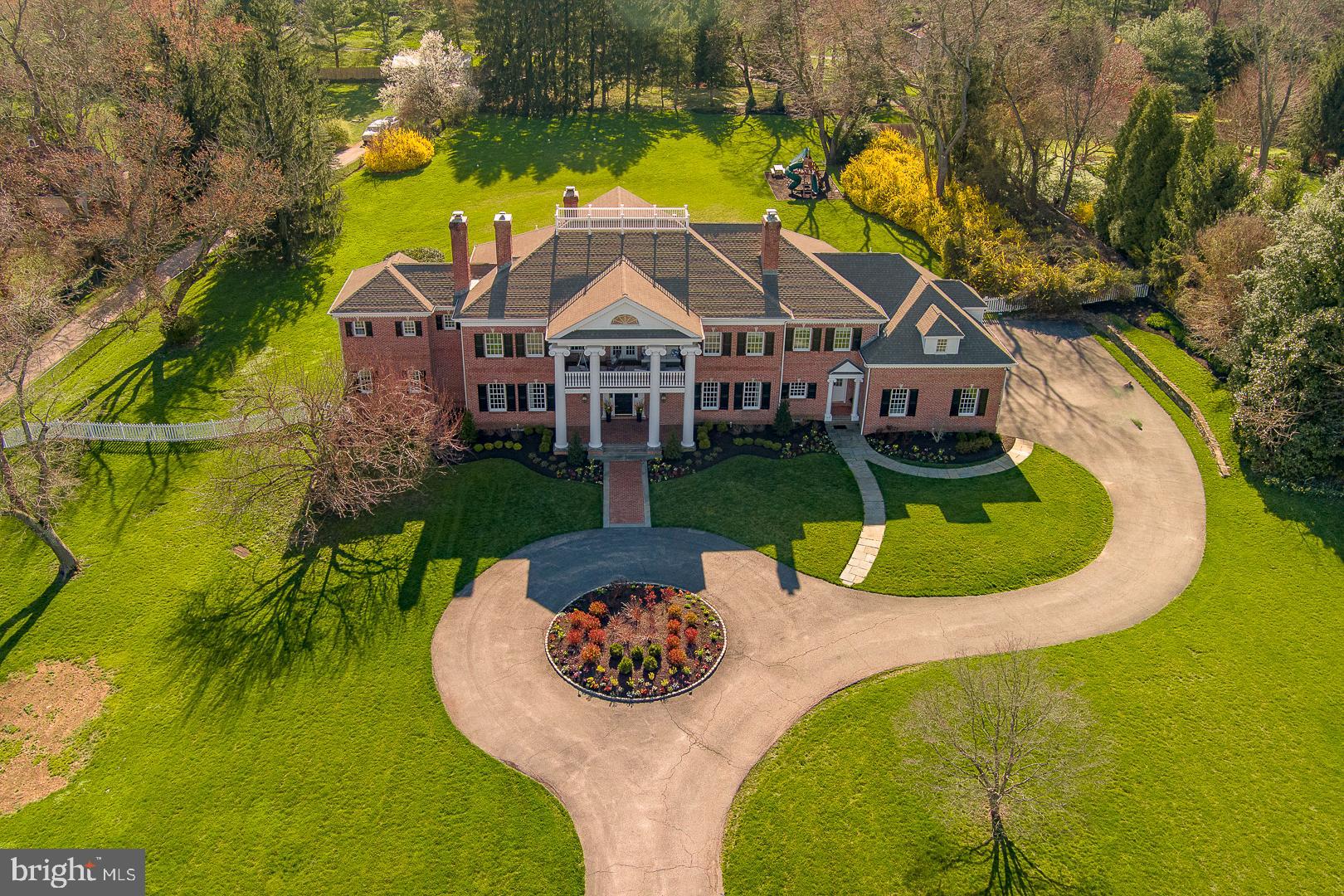 Step into the grand foyer of this Georgian-style home and be greeted by the warm embrace of traditional elegance seamlessly blended with modern luxury. Recently featured in Traditional Home Magazine alongside renowned interior designer Glenna Stone, this nearly 9,000-square-foot estate overlooks Philadelphia Country Club in the coveted Gladwyne neighborhood, a true suburban oasis.
As you enter through the arched doorway, the great room beckons with its 28-foot-high wood trusses and beams, infusing the space with a sense of comfort and sophistication. Expansive windows and French doors invite the outdoors in, offering breathtaking views of the surrounding landscape.
A graceful curved staircase leads to a circular landing and balcony on the upper level, creating an ideal setting for entertaining against the backdrop of the picturesque golf course. The dining room, adorned with a painterly emerald green silk wall covering and a cozy fireplace, exudes an elevated charm perfect for intimate gatherings. Tucked behind pocket doors, the living room strikes a balance between formality and comfort, boasting exquisite molding, built-in bookshelves, and a marble fireplace.The fully remodeled kitchen is a vision of contemporary elegance, featuring Giotto quartzite countertops, an oversized island, and slate blue cabinetry bathed in natural light. This level also offers a spacious powder room with unique tile flooring and brass accents, while a sun-soaked home gym and a vibrant, multifunctional office space cater to wellness and productivity.
The primary suite is a haven of luxury, complete with a cozy sitting area, a pass-through coffee bar, featuring a mini refrigerator and compact dishwasher that is perfect for enjoying a morning cup of coffee or a relaxing evening beverage without leaving the comfort of the suite. Indulge in a spa-like bathroom with heated tile flooring and a freestanding bathtub. Upstairs, two generously sized bedrooms each boast a fireplace and walk-in closet, sharing a large bathroom. A fourth bedroom features a beautiful bay window overlooking the expansive rear property, complemented by an en suite bathroom and walk-in closet. The fifth bedroom offers a private suite with its own ensuite bathroom, providing a serene retreat for guests or family members.
This exceptional home seamlessly marries traditional charm with modern comforts, creating an unparalleled living experience in one of Gladwyne’s most prestigious locations. Welcome to a timeless sanctuary where luxury and sophistication converge.