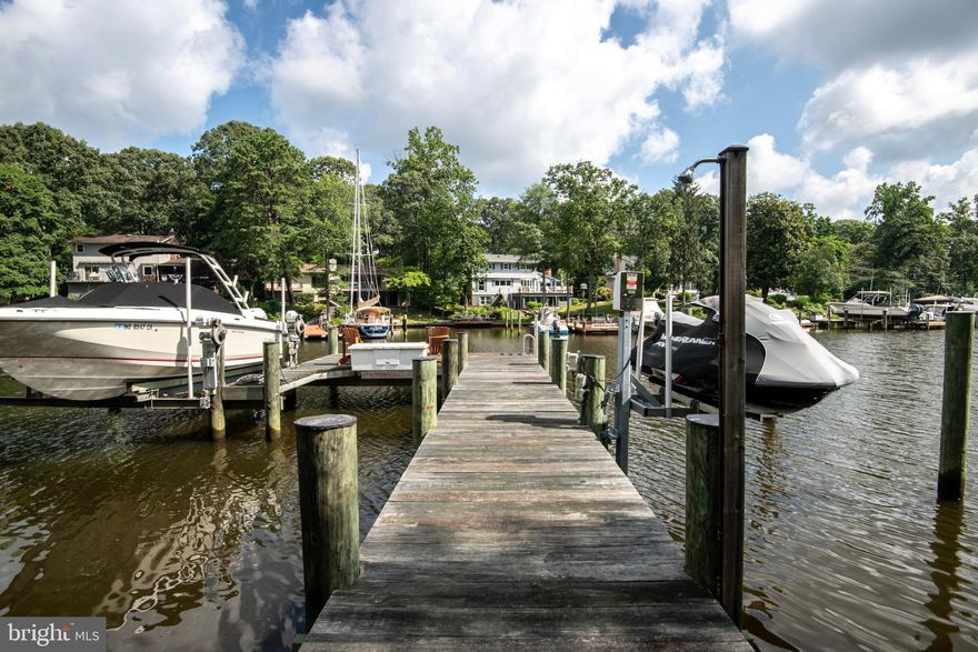 This isn’t just a home — it’s a lifestyle. Set on over 2 private wooded acres with more than 500 feet of water frontage, 34 Chartham Lane offers the rare opportunity to vacation at home every single day. Whether you're boating, paddleboarding, entertaining on the deck, or simply enjoying the view — life here feels like an amazing getaway. The private pier features a 10,000 lb boat lift, a separate jet ski lift, and an area to launch kayaks, making it easy to spend your days out on the water. After a day on the creek, come back and relax in the hot tub overlooking your peaceful, tree-lined property, or gather with friends on one of the three custom decks for a sunset drink. Inside, you'll find 5 bedrooms and 5 full bathrooms, with flexible living spaces designed to grow with your needs. The main level study and lower-level media room could easily serve as a 6th or 7th bedroom. The updated kitchen with its large island opens to a sunny living space anchored by a beautiful stone fireplace — the perfect backdrop for everyday living and effortless entertaining. The lower level offers a huge media room, ideal for movie nights, game days, or a quiet space to unwind. There’s also ample storage, giving you room to stay organized and clutter-free. Every detail was thoughtfully designed — from the HardiePlank siding and stone water table to the custom portico and irrigation system. Natural light pours through the home, highlighting water views from nearly every room and bringing the outdoors in. Located within the highly rated Severna Park school district and just minutes from shopping, dining, and commuter routes — this is a rare waterfront home that offers it all: privacy, beauty, and the convenience of everyday living. Welcome Home!