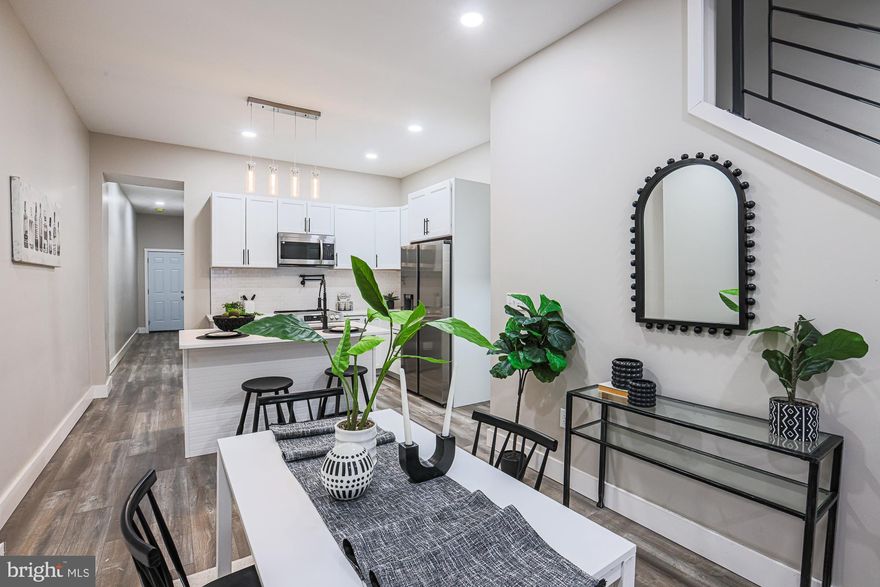 Welcome to this fully renovated porch-front brick rowhome offering modern finishes, open living, and flexible space throughout. Step inside to tall ceilings, recessed lighting, and new LVP flooring that flows seamlessly throughout the home. The open floor plan creates the perfect setting for entertaining in the living room and hosting dinners in the dining area. The spacious kitchen is a standout, featuring abundant cabinetry, ample prep space, quartz countertops, stainless steel appliances, a tile backsplash, and an island with stool seating for quick bites or casual gatherings. A main-level bedroom and powder room add flexibility and convenience. Upstairs, the light-filled primary bedroom boasts a beautiful bay window and a private ensuite bathroom with a tile-surround tub/shower combo. Two additional bedrooms and a full hallway bathroom with a tub/shower combo complete the second level. Laundry is conveniently located on this floor. The unfinished lower level offers excellent storage or the opportunity to add additional living space. Outside, enjoy a rear patio that can also be used for private parking. Conveniently located near Route 40, Reisterstown Road, Druid Hill Park and Mondawmin Mall, this move-in-ready home is a must-see. Schedule your showing today!