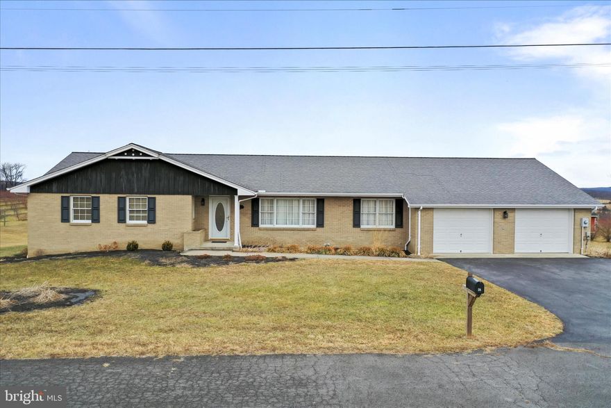 Most homes play it safe. This one starts with substance. Built in 1995 and clearly cared for ever since, this four-bedroom, three-bath home offers approximately 2,700 square feet of finished living space, including a partially finished lower level with a large family room and plenty of storage space. The layout delivers real flexibility—enough space to live comfortably today without feeling oversized or impractical.
The main level is comfortable and well-balanced, filled with natural light, hardwood floors, and a floor plan that simply works. The kitchen is functional and inviting, connecting naturally to dining and living areas that feel warm and livable rather than staged. Downstairs, the finished basement adds valuable bonus space that works well for entertaining, hobbies, or overflow living—without compromising storage or utility areas. Set on a desirable double lot, the exterior is one of this property’s quiet strengths. The yard is flat, open, and beautifully maintained, offering space that’s truly usable—not just nice to look at. From the rear of the home, you’ll enjoy mountain views overlooking a neighboring orchard, creating a setting that feels peaceful and open without being remote. A covered front porch and rear deck extend the living space outdoors, ideal for morning coffee or evenings winding down. The practical features are exactly where you want them: public water and public sewer, a two-car attached garage, a paved driveway, and a paved street. The brick exterior gives the home a timeless, grounded feel, and the overall condition reflects consistent care—not quick fixes or cosmetic shortcuts. Location is the final piece that brings everything together. Just outside of Romney and off Jersey Mountain Road, this is a proven, commuter-friendly area close to schools, the hospital, shopping, and daily necessities. It’s an easy transition for out-of-area buyers relocating to West Virginia and a smart, long-term choice for local buyers who want quality without compromise. This isn’t a flashy renovation or a trend-driven house that dates itself in five years. It’s a well-built, timeless, well-located home with real space, real views, and real value—the kind of property that quietly outperforms the market because it checks the boxes buyers actually care about.
If you’re looking for something solid, comfortable, and genuinely livable—with just enough size and presence to stand apart—this is the one to see.