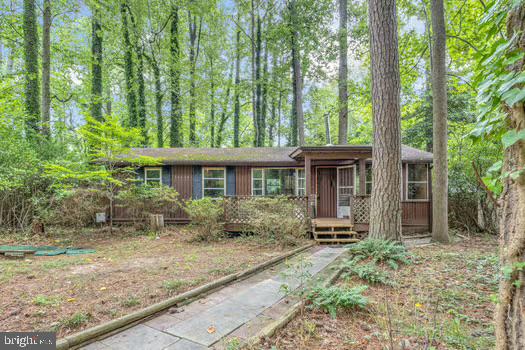 Charming log cabin the woods! Whether you are looking for a weekend getaway or a full time place to get away from it all, this is the one! Open floor plan and soaring ceilings in the main living area with family room open to dining and kitchen. Spacious sunroom that spans the entire width of the home gives unlimited options from a 3rd bedroom to another common living space. Down the hall you will find two bedrooms and a full bath with laundry. New luxury plank floors and carpet installed. Wood burning stove heats the entire place all winter long. Level back yard can be cleared up or left in a natural state. Covered front porch, rear deck, shed and more. Community access to the private beaches at the lake and the Chesapeake Bay. Close to parks, nature trails, Solomon’s Island, shopping ,restaurants and more!