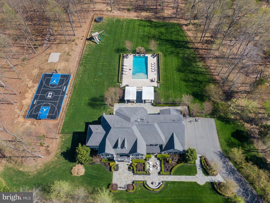 Venturing through the front gate and up the idyllic tree-lined drive and lushly landscaped grounds of this majestic residence, you'll soon realize that you're about to experience something very special. But even in your wildest dreams, your expectations are about to be surpassed in every way imaginable. Ideally situated on 15 very private and wooded acres, comes this spectacular custom estate, featuring all of the amenities that today's luxury homebuyers are searching for. A double-door entry with leaded glass welcomes you into a grand two-story foyer highlighted by two elegant and winding wood and wrought-iron staircases set upon marble floors, providing just a glimpse of what's to come. At left is the formal living room, with French doors leading to a private den/office. Opposite the living room and directly to the right of the entry is a stunning formal dining room with bold crown molding and designer tray ceiling with dual chandeliers, beckoning you to imagine scrumptious holiday meals with family and friends. With over 10,000 square feet of living space boasting 7 bedrooms, 7 full baths and 2 half baths, there's more than enough room in this stately masterpiece for each member of the family to easily find a place to call their very own. The floor plan is exquisitely open and spacious, with all of the main living areas designed with comfort and convenience in mind. When your adventure leads you into the two-story family room, your breath will be taken away by the magnificent floor-to-ceiling flagstone fireplace, flanked by walls of windows on either side to let in tons of natural light and the 700-gallon fresh-water aquarium, complete with drop-down TV.   This is likely to become the place where the family spends most of its time, as it also opens to the breakfast room and gourmet island kitchen. Speaking of which, the chef in the house will completely fall in love with the quality and abundance of custom cabinets, along with gleaming level 4 granite counters, commercial-grade appliances, and thoughtful conveniences like the vegetable prep sink in the center island, the two dishwashers, and the pot filler over the 6-burner cooktop with grill. There's also a menu-planning station with built-in desk and additional cabinets and storage. For wine connoisseurs, you'll appreciate the floor-to-ceiling wine fridge.  An oversized walk-in pantry provides additional storage with shelving and slide-out drawers. After dinner, relax and entertain in the finished basement game room or home theater, or retire to one of the many bedrooms throughout the home.  The graciously renovated owner's en-suite retreat features a romantic fireplace, dual closets with built-in organizers, a wet bar with beverage fridge, and an elegant bath with dual extended vanities, heated floors, an oversized shower and standalone tub. There are two large laundry rooms (main floor and upstairs) for convenience and the property features a finished 4-car garage to house your prized vehicles and toys.

For outdoor entertaining, this home boasts one of the largest residential pools in Loudon County, built by Lewis Aquatech, which becomes the centerpiece between two open-air pavilions with travertine decking. There's also a fully-equipped outdoor kitchen/barbecue with seating from which to host "talk-of-the-town" summer pool parties. For fitness buffs, an enclosed sport court with outdoor lighting allows you to burn off a few calories before savoring freshly brewed iced mochas beneath the patios at sunset. Located just minutes to Brambleton Regional Park and Golf Course, and only 1.5 miles to the renowned Brambleton Town Center with restaurants, shopping and entertainment, this unique home in the Estates at Evergreen is a place where even the simplest of memories were meant to be created, shared, and treasured for years to come.