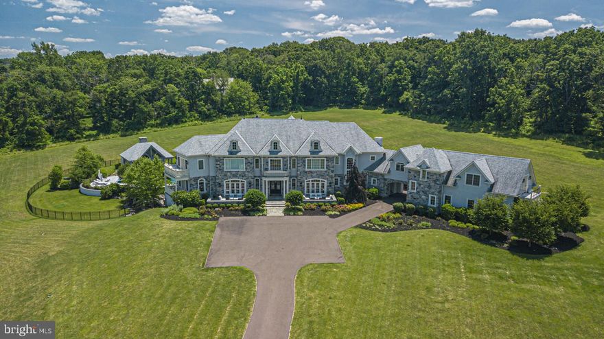 This exquisite custom estate on 10 gorgeous acres in Upper Makefield provides the perfect setting for a luxurious, entertaining lifestyle. Beautifully built in 2013 by Mack & Roedel and professionally decorated by Rittenhouse Interiors there are 5 Bedrooms, 7.4 Baths including an attached Guest House. Constructed with optimum materials and upgraded at every turn including stunning millwork, moldings, elevator, lovely bluestone courtyards, 4 car garage and many other custom features. The dramatic two-story entrance foyer with marble floors, a floating staircase and incredible Living Room with wall of windows, exquisite moldings and gas fireplace set the stage for the true beauty and quality the home exudes. The first floor also features a Library with leather paneled walls, a private Study with veranda, Flex Room with Bath, and a spectacular Dining Room with Butler's Pantry perfect for large dinner parties. The grand Gourmet Kitchen is distinctive because of its size, layout, design and an abundance of the very best appliances and amenities; comprising of mirrored subway tile backsplash, custom tile work, marble counters, banquette seating, 2 sinks, 2 islands, built-in Bar and open to the Family Room with coffered ceiling. The second floor offers an impressive Master Suite that includes a dual sided fireplace, Sitting Room with a balcony highlighting breathtaking views, luxurious Bath which has a fireplace by the Jacuzzi tub and other elegant features, 3 Additional En-Suite Bedrooms and Laundry Room complete this floor. The third floor offers spacious flex space which is currently used as a playroom. The Lower Level is truly astonishing and begins with a reception foyer and continues with a wine tasting/cigar lounge with stone wall and temperature controlled wine cellar, a yoga studio with Full Bath, Laundry Room, Living Room, Billiard Room, 2 lane Bowling Alley, half Bath, Karaoke stage, and an astonishing 12 seat zinc topped professional Bar. The expansive outdoor area continues to amaze and impress offering many entertaining and relaxation opportunities: a wood burning stone fireplace and living room with coffered ceiling at the upper patio, ability to dine alfresco and to cook under the pergola in the professional outdoor Kitchen or to lounge by the pool with a pavilion featuring another stone fireplace and a half bath; all of these wonderful elements include magnificent iconic Bucks County views.