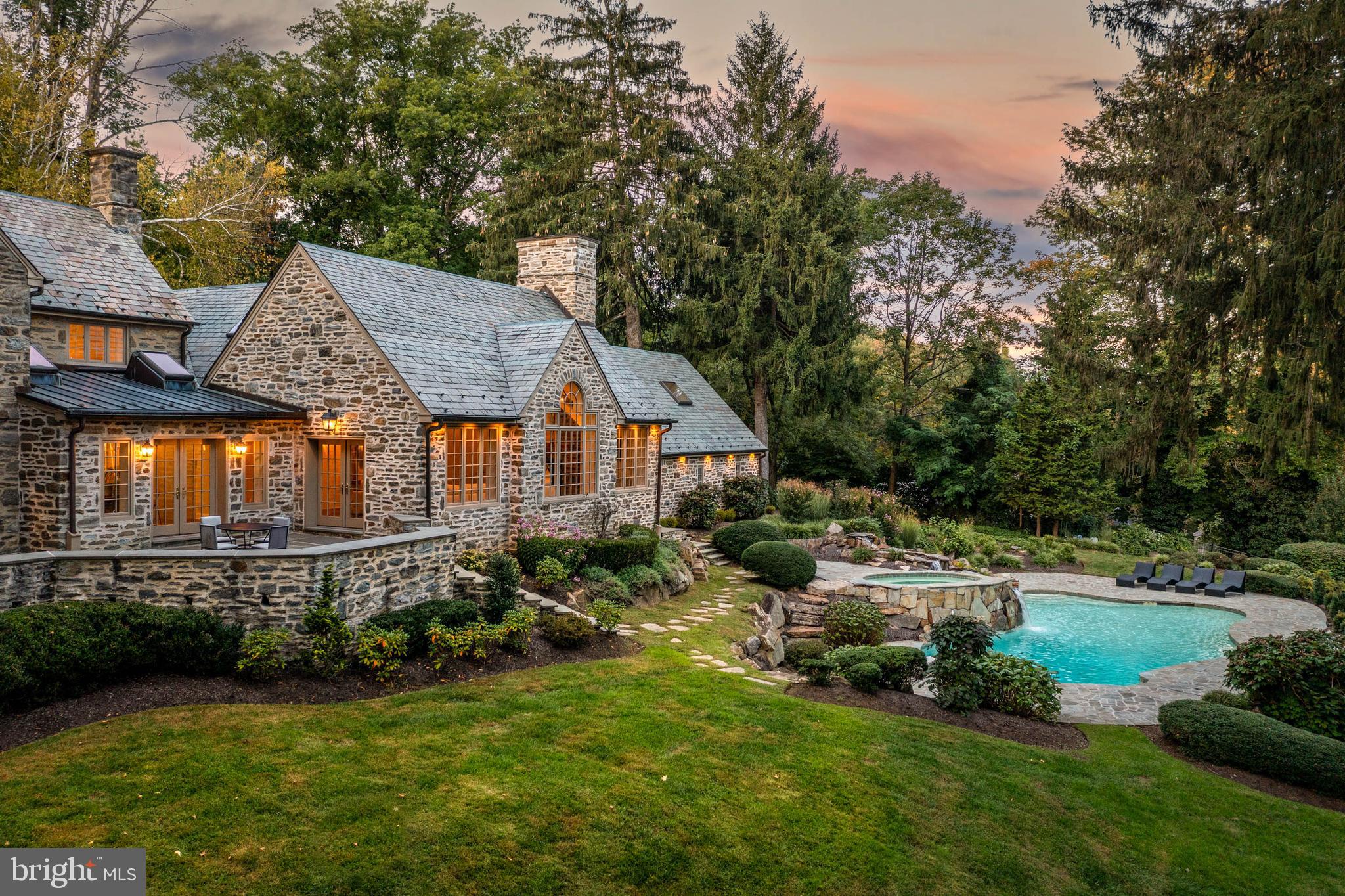 Breathtaking gated estate and restored Walter Durham masterpiece. "Braebank” is a historic and architectural treasure renovated completely to the highest luxury standards. Perched atop 6.67 sweeping acres of utter privacy and lush views, the home’s quintessential fieldstone exterior is finished with slate roof, copper gutters and wrap-around flagstone terraces that embrace the tranquil setting at every turn. The stunning grounds are punctuated by a trickling creek, gazebo and a glistening pool with spa and waterfall positioned to overlook the sun-filled views. Tucked on a quiet road, shared by some of the Main Line’s finest estates, pull up to the iron privacy gates completed with gas lanterns and down to a motor court lined with original stone walls and ending at a five car garage. The exquisite and timeless exterior echoes the breathtaking interior. No stone was left unturned in raising this timeless treasure to the finest modern day standards. Walk through the classic original door to a foyer that warms you with original wide-plank hardwood flooring. The elegance of the home is immediately showcased by a curved staircase framed by a striking and pristine Schoenbeck crystal chandelier. From the foyer, step down to a living room with soaring ceiling heights, original built-ins and molding, fireplace, glorious light with exposure on three sides and french doors to the grounds. A Mahogany office is completed with exquisite millwork, fireplace, wrap-around built in shelves and also steps out to the terrace. Both the Living Room and Study are quintessential Walter Durham features. A grand dining room is large enough to fit the extended family. It is finished with beautiful molding and overlooks the rolling hills with a large bay window. The family room could have been plucked from the pages of a design magazine with a dramatic cathedral ceiling, exposed trusses, floor to ceiling stone mantel and Palladian window overlooking the glimmering pool and grounds. A flowy, open layout that is ever sought after but hard to achieve in these elegant old stone houses connect this exquisite family room to a spectacular kitchen and breakfast room space. Also finished with a vaulted ceiling, the breakfast room is drenched with light from skylights and glass paneled double doors to the terrace. THe kitchen is fit for a gourmet with a large center island and high-end stainless-steel appliances. Custom white shaker cabinets and quartz countertops finish this kitchen with the utmost style and taste. Upstairs, the primary suite boasts another vaulted ceiling, an extremely rare feature for a home of this era. A large walk-in closet awaits the custom finishes of the Buyer and the primary bathroom has deep soaking tub, large tile shower with frameless glass door and double vanities. A private terrace completes this bespoke primary suite. Two additional bedrooms both with renovated ensuite bathrooms are in close proximity to the Primary. Further down the hallway, two additional bedrooms share a jack and jill bathroom and a cozy homework space. Another standout feature, the second floor is finished with a warm and light filled bonus room, which has its own entrance to the outside. Perfect for an upstairs family room, au-pair space or fancy expanded office. Off the kitchen, a finished basement boasts a full bathroom and room enough for gym and a theater and additional hangout space. This grand project has been completed masterfully by a reputable Main Line builder who specializes in historic renovations. Utterly tranquil and yet centrally located with close access to major roadways, shops, train lines. Award winning Lower Merion School District. Includes partial house generator.