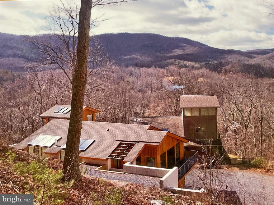 First time offered and move-in ready! Beautiful custom "Deck House" with wood burning fireplace is nestled in the woods on a mountainside offering views of the Blue Ridge Mountains. Multi-level home with primary bedroom on the main level, offers one-level living with room to spare (Main level laundry). The clean, classic simplicity of the structure is drawn from its post and beam framing system. The contemporary design that is crafted of mahogany, masonry, and glass is a symphony in light. Sloping high 18' ceilings on the main level cap an interior that is warm, neutral, and informal. Expansive windows with wells framed in mahogany bring the outside in. Expansive kitchen has natural birch cabinets and granite countertops. Extra wide 36" doors make this stunning home handicap accessible. Floors are either bamboo, tile, or concrete. Radiant heat warms tile floors. Solar panels and multi-geothermal wells provide electricity for low electric bills. Main house also has a sauna, exercise room, and large workroom.
A 2017 addition provides comfortable private space for guests and includes an "Orangerie", a 3-story greenhouse with a dramatic spiral staircase, as owner was a landscape architect. Hence, this beautiful property is surrounded by exquisite plantings and trees for your delight.
Additional buildings includes an attached oversized garage with workshop, a 32x24' two-story utility garage for tractors and equipment with electricity and its own well, and a 20x24' garden house.
"BobKat Woods" is located just outside the lively towns of Sperryville and  Washington, VA  (home of the Michelin 3-star "Inn at Little Washington, is minutes from the Shenandoah National Park, well-known wineries, eateries, and art galleries, that make rural beautiful Rappahannock County so unique.