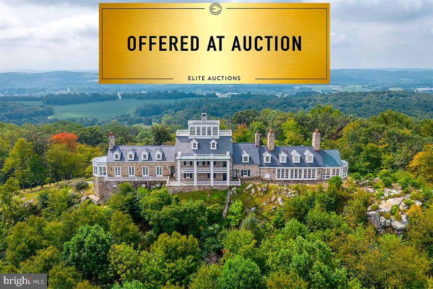 AUCTION, 10/23/2023, at 11:00 AM.  Previews are by appointment until the Auction day.

A private estate on 132 +/- acres
This property boasts unique features offering the utmost privacy, perched almost 800 feet above the Susquehanna River. It offers stunning 360-degree views of the surrounding five counties. Roundtop Lane has a rich history; today, it's accessible via a gated entrance. As you drive through, you'll pass by private ponds and lots of wildlife until you reach the summit of Roundtop, where you'll find the sprawling main house.
The original house was constructed with 27-inch-thick solid stone walls and steel and concrete floors between each level. In the 1990s, the current owner built both wings east and west of the main house, maintaining the same construction quality as the original structure, including slate roofing with copper spouting and gutters. These design elements are evident in all the other structures on the property.
You can use the stairs or elevator between floors inside the main house. On the first floor, you can relax in the open great room with exposed wooden beams, two fireplaces, and a wall of windows overlooking Lancaster County. At the end of the great room, there's a warm and inviting sunroom where you can enjoy watching winter sunsets. The indoor pool at the other end of the house provides year-round access to swimming while taking in the views. The pool features an ozone filtration system that provides a chemical-free odor of a pool inside your home. The pool area also has standalone humidity and climate control. The pool is heated, along with the stone floor around it.
You can access a full guest suite from the ground floor with a full bathroom. There's also a large walk-in cooler for your goodies or fine beverages. On your way up to the top floor, you'll have access to five more bedrooms, including an owner's suite with a complete kitchenette, sitting room, and two bathrooms. Alternatively, you could walk onto your private balcony to enjoy the sunrise. Once you arrive at the top floor, you can enjoy 360-degree unmatched views from your private climate-controlled conservatory.
You'll pass a serene koi pond as you leave the main house and drive down the lane. After rounding the corner, you'll find yourself at the outdoor pool and pool house with all the amenities. The 24x80 pool provides ample space for you to enjoy total privacy. The pool house features a kitchenette with an island, open vaulted ceilings with an open timber frame, and a floor-to-ceiling stone and brick fireplace. You can gaze beyond the pool and up the slate stairs to the open yard, perfect for outdoor games and activities. The owner previously used this area to park his private aircraft. Electrical wiring is in place and can be restored to illuminate night flying.
The guest cottage boasts tall, vaulted ceilings, a floor-to-ceiling stone fireplace, and reclaimed barn wood floors. You can enjoy the view of a private pond from the cantilevered deck or hear the babbling spring from your private screened porch. The cottage also has a delightful kitchenette, pantry, and extra built-in freezer. The full bathroom features an open-concept tile walk-in shower. Upstairs, there's a loft with a powder room and great views of the pond.
The property is complete with a place for your toys. The barn is entirely built and wrapped with cedar and slate and has a cupola to allow light into the second-floor studio. The barn can accommodate 8-plus vehicles and has full HVAC systems, a full bath, a powder room, and a washer and dryer.
All structures have separate backup power generators to ensure you'll never be without power. For more specific details about utility information for each structure, please look at the features sheet provided.