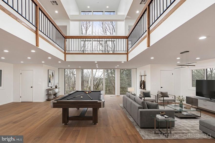 Step into a world of refined contemporary design with this fully renovated 7,800-square-foot architectural home featuring 7 bedrooms and 9 bathrooms, nestled among the trees. Dramatic vaulted ceilings and expansive floor-to-ceiling windows flood the interior with natural light while framing serene woodland views, creating a seamless connection between the home and its natural surroundings.

Warm hardwood and natural stone flooring introduce rich, earthy textures throughout the open living spaces, complemented by distinctive brick architectural elements that add character and depth. The home’s thoughtfully designed layout features two distinct wings—the east wing houses the dramatic two-story great room along with four bedrooms, while the west wing offers a private retreat with the primary suite and additional guest suite. The striking great room with balcony overlook creates an incredible sense of scale and serves as a centerpiece for both everyday living and entertaining.

Outside, multiple decks and terraces extend the living space into the landscape, offering ideal settings for gatherings, outdoor dining, or simply enjoying the peaceful wooded setting. Located just steps from the Baisman Run trailhead at Oregon Ridge Park, this home offers immediate access to miles of scenic hiking and nature trails. With its bold contemporary architecture, unique design features, and impressive scale, this home is perfectly suited for memorable entertaining and sophisticated modern living.