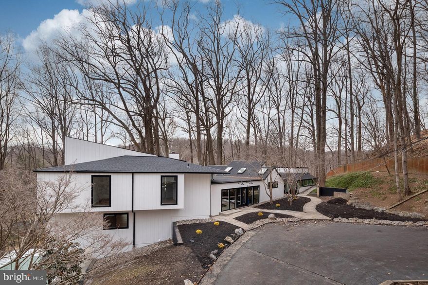 Step into a world of refined contemporary design with this fully renovated 7,800-square-foot architectural home featuring 7 bedrooms and 9 bathrooms, nestled among the trees. Dramatic vaulted ceilings and expansive floor-to-ceiling windows flood the interior with natural light while framing serene woodland views, creating a seamless connection between the home and its natural surroundings.

Warm hardwood and natural stone flooring introduce rich, earthy textures throughout the open living spaces, complemented by distinctive brick architectural elements that add character and depth. The home’s thoughtfully designed layout features two distinct wings—the east wing houses the dramatic two-story great room along with four bedrooms, while the west wing offers a private retreat with the primary suite and additional guest suite. The striking great room with balcony overlook creates an incredible sense of scale and serves as a centerpiece for both everyday living and entertaining.

Outside, multiple decks and terraces extend the living space into the landscape, offering ideal settings for gatherings, outdoor dining, or simply enjoying the peaceful wooded setting. Located just steps from the Baisman Run trailhead at Oregon Ridge Park, this home offers immediate access to miles of scenic hiking and nature trails. With its bold contemporary architecture, unique design features, and impressive scale, this home is perfectly suited for memorable entertaining and sophisticated modern living.