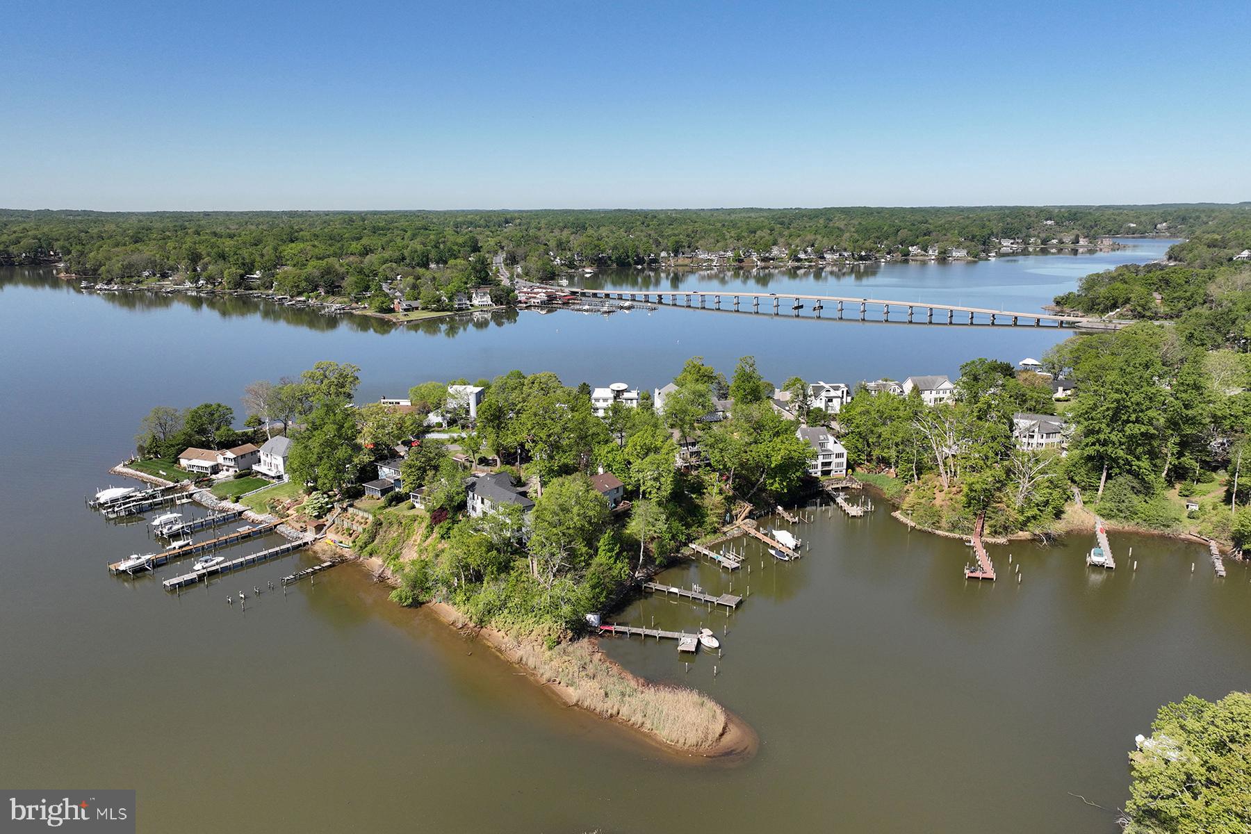 3015 Friends Road is perched on a stunning point of land where the South River meets the protected waters of Boyds Cove. The views down the South River towards the Chesapeake Bay are truly endless! This custom-built home with 456 ft of waterfrontage is everything you’d hope for in a modern waterfront retreat. Built in 2021, it blends contemporary design with the relaxed elegance of coastal living and every detail has been thoughtfully crafted to make life feel effortless. From the moment you walk in, you're welcomed by a soaring two-story foyer anchored by a dramatic light fixture — a striking first impression that sets the tone for the rest of the home. From there, the wall of glass overlooking the South River takes center stage and immediately lures you to the waterside.
The heart of the main level is an open-concept great room featuring the kitchen with quartz waterfall, dining area, and family room with a stylish raised gas fireplace. The spaces flow easily in a bright, airy layout designed for both easy living and entertaining. The gorgeous, oversized island is perfect for casual meals, conversations, or hosting with ease. A walk-in pantry adds function, while beautiful light fixtures lend a contemporary, curated feel throughout the space. Step onto the spacious composite waterside deck, through 8 ft doors, which offers impeccable views, al fresco dining and comfortable seating areas. The layout is as flexible as it is beautiful. There’s a main-level water view bedroom (currently set up as an office) with a full bathroom. Upstairs, the primary suite is a peaceful escape, featuring a private office or sitting room that overlooks the water. The walk-in closet has been perfectly designed to handle an extensive wardrobe. The bathroom truly feels like a spa with deep soaking tub, custom tiled shower, WC and dual sink vanity. Two more bedrooms, each with their own bathroom, provide space and privacy for everyone.
The finished, walk-out basement is a great place to hang out with friends, with its’ custom bar and space for a home theater. There’s also another bedroom, with sliding glass door to a waterside patio, and full bathroom. From the main level, there is access to an upstairs guest suite, thoughtfully designed to have a separate entrance and lots of closet space to provide guests with privacy and comfort. Outside, enjoy everything that makes living on the South River so special: a private pier tucked into a protected cove, multiple vantage points for soaking in the river views, an outdoor shower, and lush, thoughtful landscaping that frames the home beautifully. Around the corner by boat are multiple restaurants and fuel docks. This property offers the rare combination of a new home in pristine condition, panoramic views and protected pier, public water and sewer, and easy access to downtown Annapolis and Route 50.