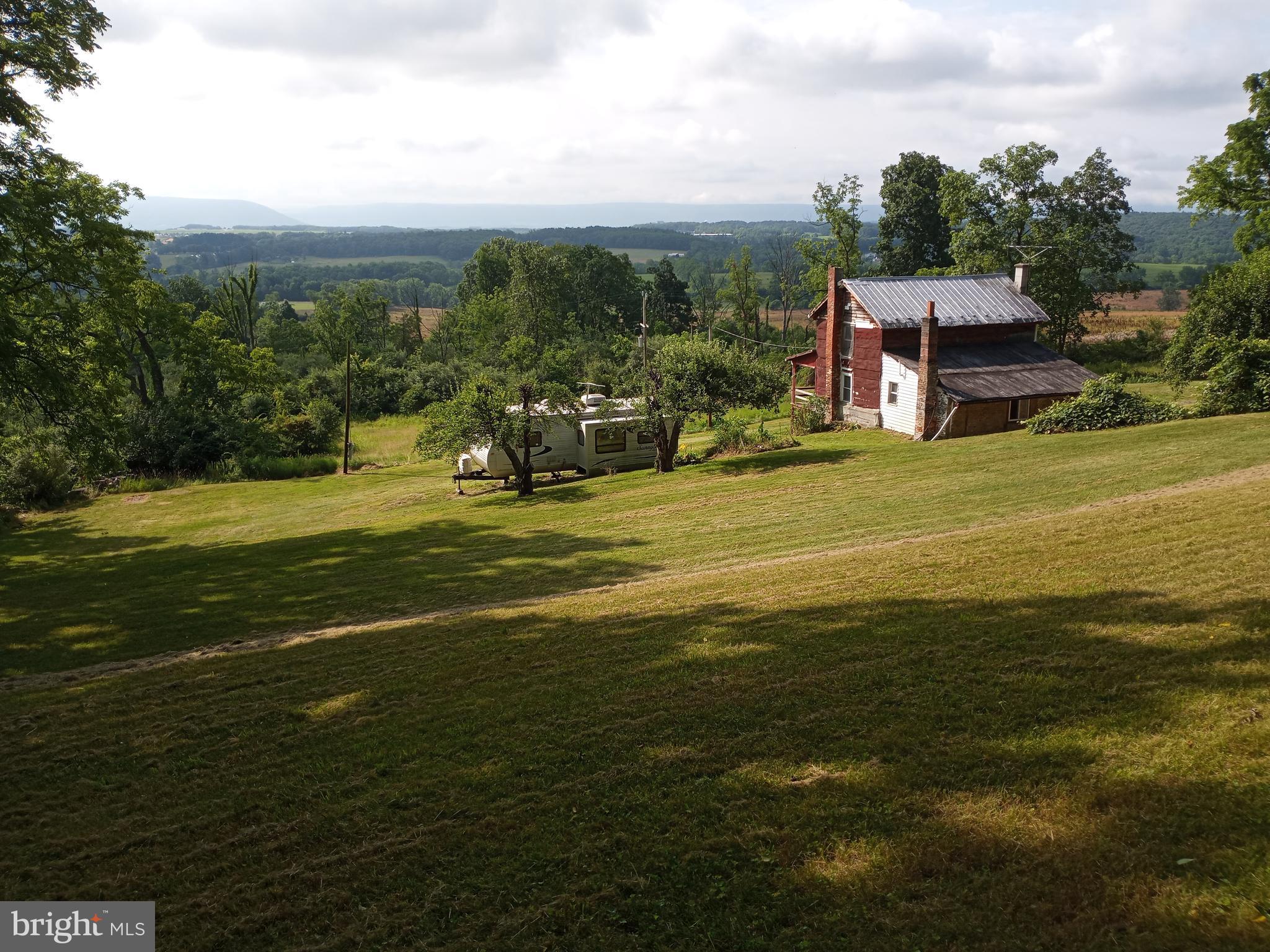 Nestled at the base of Purdue Mountain and overlooking Nittany Valley, you will discover this one of a kind beautiful and cleared one acre parcel of land. Stunning, secluded, serene, lush, rustic, tranquil and panoramic are just a few words that describe this rare find. Surrounded by over 400 acres of undeveloped pastures and woods is an oasis offering many options. Currently, in use as a camp for hunting or just relaxing, providing a small 768 sq. foot 2-story home with 2 bedrooms, living room, kitchen and a bath, plus a Sunny Brook Winnebago Camper that sleeps 2 and is in very good condition. You will have plenty of space for guests and friends. The home was built in the mid 1800’s and is in rough condition and needs a rehab. Another option would be to remove the home and build the home of your dreams. At the very back top of the parcel one can get a glimpse of Beaver Stadium on a clear day making it the ideal spot for such a venture. The front and back yards offer plenty of room for a large garden to augment the mature apple and pear trees and grape arbor. Two outbuildings top off the property. The first is a solidly built block barn with a functioning walk-in cooler to store meats and produce complete with electric and water service. Second is an old smoke house now used to store yard tools. This property is a unicorn in that it has a Bellefonte mailing address but is in Patton Township within the State College Area School District. What a find – located just 5.5 miles form Beaver Stadium and only an 8-minute drive by car. GPS directions may use Kline Lane and not Kline Road.