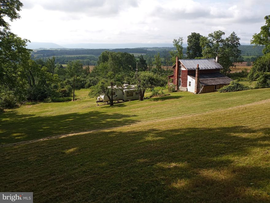 Nestled at the base of Purdue Mountain and overlooking Nittany Valley, you will discover this one of a kind beautiful and cleared one acre parcel of land.  Stunning, secluded, serene, lush, rustic, tranquil and panoramic are just a few words that describe this rare find.  Surrounded by over 400 acres of undeveloped pastures and woods is an oasis offering many options.   Currently, in use as a camp for hunting or just relaxing, providing a small 768 sq. foot 2-story home with 2 bedrooms, living room, kitchen and a bath, plus a Sunny Brook Winnebago Camper that sleeps 2 and is in very good condition.  You will have plenty of space for guests and friends.  The home was built in the mid 1800’s and is in rough condition and needs a rehab, or complete removal and instead build the home of your dreams.  At the very back top of the parcel one can get a glimpse of Beaver Stadium on a clear day making it the ideal spot for such a venture.  The front and back yards offer plenty of room for a large garden to augment the mature apple and pear trees and grape arbor.  Two outbuildings top off the property.  The first is a solidly built block barn with a functioning walk-in cooler to store meats and produce complete with electric and water service.  Second is an old smoke house now used to store yard tools.  This property is a unicorn in that it has a Bellefonte mailing address but is in Patton Township within the State College Area School District.  What a find – located just 5.5 miles form Beaver Stadium and only an 8-minute drive by car.  GPS directions may use Kline Lane and not Kline Road.