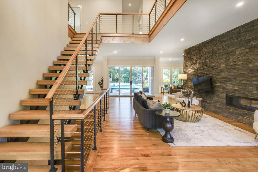 Welcome to this stunning contemporary home in quiet location on a non-thru street with in-ground, salt water pool.  This gorgeous four bedroom, four full-bath residence is a private retreat that's only minutes away from DC and MD.  With its style, location and privacy, this residence is definitely the one you've been looking for!  
The front entrance opens to breathtaking views through to the backyard and show-stopping pool with waterfall edge.  
Gorgeous wood floors throughout the main level warm the space and complement the butcher block floating stairs with cable railing.  Luxury finishes include crown molding throughout and recessed lighting. 
The light-filled home's foyer is open to the top floor enhancing its spacious feel and highlighting the striking stacked stone wall with 2-sided gas fireplace.  
The formal dining room has large windows and is gracefully illuminated by a gorgeous chandelier.  
The kitchen boasts a huge island, large walk-in pantry, wine fridge and a wet bar.
The main floor also has a large family room, library with built-in bookshelves and gas fireplace, and a  full bath.  
Head up to the second-floor mezzanine, which is open to the foyer and living room below, every window on this floor has private tree-top views! 
The massive primary retreat has a large walk-in closet with skylight and wall safe. The primary bath includes double sinks, oversized shower, soaking tub and a private water closet with bidet. 
There is also a large open area that is perfect for an office, play room or yoga retreat, the possibilities are endless!  Two additional bedrooms share a Jack and Jill bath with double sinks and bathtub.  The laundry room is also conveniently located on this level.  
The lower level includes a large rec room with 2-sided wet bar and its own gas fireplace along with an additional bedroom, full bath, exercise room and utility room with additional storage.  There is also access to the 2-car garage and front yard.   
The home feeds into the coveted McLean High School pyramid. This exceptional property is a timeless treasure, seamlessly blending sophistication, functionality and beauty.  Don't miss your opportunity to own this piece of paradise!