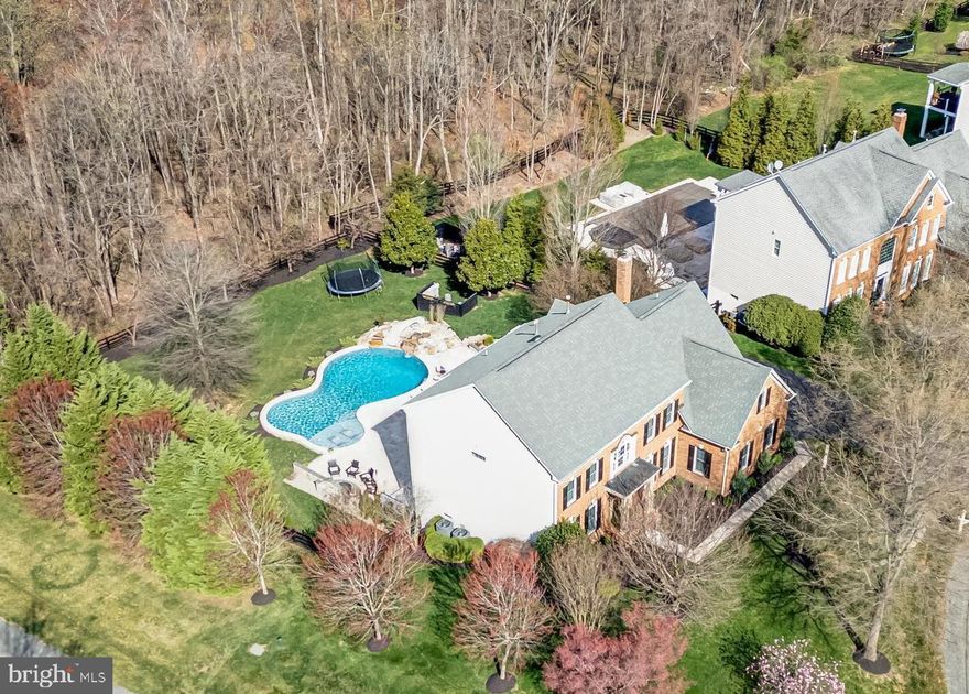 Multiple offers received.   Welcome to your new haven, where luxury meets tranquility in this recently updated Winchester Homes Belmont model. Situated on a half-acre homesite, this oasis backs onto the lush Lenah Run Conservatory, providing a picturesque backdrop for your everyday retreat. With over 5200 square feet spanning across three spacious levels, this residence boasts a myriad of enhancements that exude both style and functionality, ensuring a purchase you can be proud of. Step inside to discover the seamless blend of elegance and comfort, beginning with the refinished cherry hardwood floors in a matte finish, & the soothing neutral palette that envelopes the entire home in warmth. As you enter, be greeted by the grandeur of the curved staircase, now adorned with wrought iron balusters for a modern twist, along with a new RH chandelier. To your right, a spacious home office awaits behind French doors, offering a serene space for work or study. The formal living and dining areas to your left beckon with their generous proportions, enhanced by intricate trim details &expansive windows adorned w/ plantation shutters. Venture further into the heart of the home, where culinary delights await in the recently renovated kitchen. Professionally painted cherry cabinetry, Dolomite stone countertops, & top-of-the-line LG stainless steel appliances create a chef's paradise. French doors lead to a Trex deck overlooking the lush backyard, complete with a Travertine patio and inviting custom pool—a perfect setting for outdoor gatherings.  Within the kitchen, a convenient planning desk awaits, providing an organized space for daily tasks. Adjacent to this, the updated mudroom boasts built-in storage for backpacks, shoes, & coats, alongside a spacious double door closet for additional belongings. Continuing through the main level, the powder room off the foyer has been elegantly renovated. The great room, seamlessly connected to the kitchen, offers an expansive layout highlighted by a wall of windows overlooking the backyard. Here, a striking full stone two-story fireplace w/ insert & mantle commands attention as the room's centerpiece. Completing this inviting space, a rear staircase provides convenient access to the upper level. The upper level unveils a luxurious primary suite, boasting a tray ceiling, dual walk-in closets, & a spa-like ensuite bath adorned w/ upscale tiles & granite countertops, a seamless glass enclosed shower, & Jacuzzi tub.  Three additional bedrooms, each w/ their own updated bath, offer ample space & comfort for family and guests. A convenient updated laundry room w/ utility sink completes this level, ensuring effortless daily routines. Descend to the lower level, where there are multiple zones for all kinds of play, a large recreation room has plenty of space for movie watching, gaming and lounging. Newer plush carpeting & a convenient wet bar sets the stage for relaxation and entertainment. Two large dens provide versatile spaces for work or leisure, with an updated full bath & storage. This level has direct access to the patio & hot tub which invites you to unwind amidst the serene surroundings. Outside, a large stone backed, iron fire pit provides for a courtyard style sitting area. The expansive travertine pool deck w/ natural stone accent walls, integrated  lighting create an idyllic retreat for all ages. The pool showcases two custom rock waterfalls framing the exhilarating slide & an expansive tanning ledge with lighted bubblers. The home's lush landscaping, stone pathways, and opulent landscape lighting blends seamlessly with the nature Conservancy backdrop, offering privacy and serenity. With ample lawn space & full rear fencing, this home is perfect for both play and pets. Nestled within the sought-after Lenah Run community, residents enjoy access to walking trails, a community pool, & a variety of year-round  HOA sponsored events.  Lenah Run, you will love living here. Roof-2018.