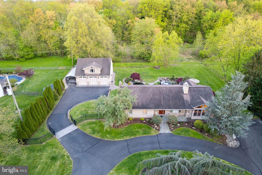 Have you always wanted to live in a beautifully crafted mountain home full of textures and timbers nestled by a bubbling creek and waterfall? Now you can live your dream. And only a five-minute drive to downtown Doylestown! This is one floor living done right in a completely remodeled home with a fantastic custom addition creating a flexible floor plan overlooking a truly spectacular outdoor landscape. A circular driveway leads to an automatic gate opening to a fenced property with a terrific three car detached garage. This property is a slice of heaven backing to the vast fields of Del Val University. Your own woods lead to trails and fields to enjoy along with the serenity of being connected to preserved land. The bones of the original ranch home remain and can be expanded into a larger first floor and even a second floor but everything else has been remodeled with the great room addition as the heart of it all. Muscular timber frame, cathedral ceilings of tongue and groove pine, stone floors with radiant heat, walls of windows, a stone wood burning fireplace, glass doors to the spectacular multi-level patio all combine to create a mountain home ambiance. The fireplace is two sided so the fire can be enjoyed in the living room as well as the great room. A custom designed Sony smart TV and Sonos surround sound connected to high end Totum speakers create a fantastic entertainment experience. Wood floors are found throughout the main part of the home with the exception of the gorgeous custom granite floors in the freshly painted kitchen with new tile backsplash and a dining area. Decorative lighting above the expansive cabinets is a finishing touch. Three generously sized bedrooms with good closet space share a full bath on the main floor. Wiring has been upgraded to accommodate an included generator. The basement has been partially finished into a rec room with a second full bath, carpeting and a soapstone wood stove. Sliders lead you to the lower-level patio. And what an outdoor space! Extensive landscape lighting, stone sitting walls, paver patios, stamped concrete with a fossil effect created with plants from the property, two waterfalls and two spectacular stocked koi ponds. Surrounded by specimen plants these low maintenance water features create an amazing mountain stream ambiance. The newer five-seat hot tub is tucked beside the waterfalls and plantings for ultimate relaxation. Close by the detached garage with half bath is outstanding and perfect for a professional shop or car collection. 3 bays with 9-foot oversized garage doors, one bay has a two-story vaulted ceiling just right for a car truck lift. The fully insulated 24’x31’ second floor has a bay window and side window and can be converted to a 744 sq ft living space or is great for storage, with a half bath plumbed for hot water. The quality built 1,076 sq ft oversized garage inside measures 30.75’x35' with a 10’ ceiling, 6" studs and is fully insulated with a newer commercial quality Mitsubishi Mr Slim heating and air conditioning system and has separate 200-amp electric service and a 60-gal Craftsman Professional air compressor with air line running to the bays. Car parking of at least 20 cars easily fit across the large circular driveway, rear driveway parking area and front side parking area. Fabulous location in move in condition and close to major routes and Central Bucks Schools