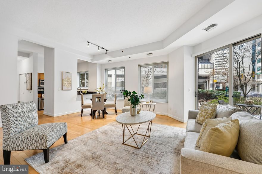 Experience effortless urban living in this thoughtfully maintained 2-bedroom, 2-bathroom main-level condo situated in the heart of downtown Bethesda. The freshly painted interior welcomes you soaring high ceilings and rich hardwood floors that flow through the main living area. Natural light pours into the open living and dining space through expansive windows, while a sliding glass door leads to a patio offering walkout accessibility directly to the street. The updated kitchen is equipped with stainless steel appliances and a convenient kitchen hatch that ensures seamless entertaining and easy access to the dining area.
The split-bedroom floor plan provides maximum privacy, featuring two generously sized bedrooms finished with wall-to-wall carpeting and ample closet space. This prime location offers an unparalleled lifestyle of convenience; you are positioned directly across from the Bethesda Metro station and bus terminal, and just blocks away from the area's premier dining, boutique shopping, and entertainment venues. For outdoor enthusiasts, the renowned Capital Crescent Trail is only a short distance away, offering miles of scenic walking and biking paths.