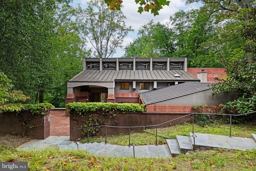175 Old Gulph Road isn’t just a home—it’s a work of art, designed with intention and presence. From the moment you arrive, its striking rooflines and sculptural silhouette set it apart, framed by professional landscaping and a circular drive.

The elevated foyer opens to vaulted ceilings and a spacious living and dining area, where a wall of windows floods the space with natural light and showcases sweeping views of the 1.58-acre wooded lot. Just beyond, ferns blanket the landscape, creating a serene backdrop to enjoy from the private deck.

The heart of the home—a Great Room, breakfast nook, and chef’s kitchen—unfolds with ease. Dark Saltillo tile, a gas fireplace, and access to the outdoors make the space as inviting as it is functional. The updated kitchen features granite counters, a SubZero refrigerator, Bosch range, Fisher & Paykel double-drawer dishwasher, and a walk-in pantry.

A sunroom, fitted with Pella windows and custom built-ins, serves as a luminous retreat—an indoor atrium where nature and design meet. A flexible office or bedroom, powder room, laundry, and two-car garage complete the first floor.
Upstairs, the primary suite feels like a private sanctuary: vaulted ceilings, a fireplace, built-in cabinetry, two large walk-in closets, and a spa-like bath with a soaking tub, glass shower, and double vanity. Two additional vaulted bedrooms with generous closets share a hall bath.

This property is as practical as it is beautiful, with 2-zone HVAC, security system, LED landscape lighting, Ipe decking, brick pad parking, and a generator.

All just minutes from Center City, King of Prussia, regional rail, 76, 476, and award-winning Lower Merion schools. 175 Old Gulph Road isn’t simply a home. It’s a statement, a retreat, and a rare chance to live in harmony with nature.