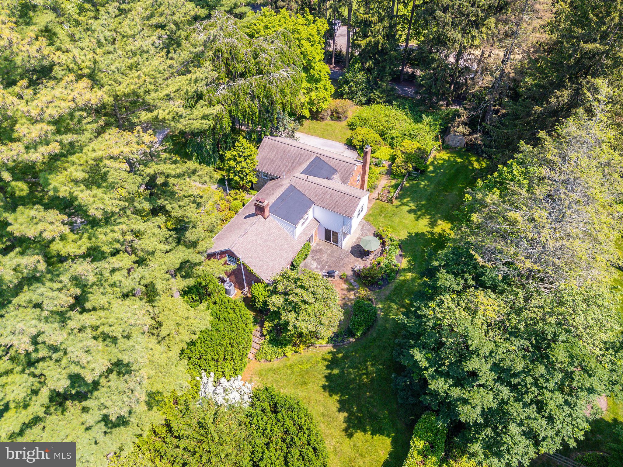 Set on a generous and level 0.89-acre lot in one of Radnor Township’s most desirable neighborhoods, this rare opportunity offers unlimited potential for renovation, expansion, or brand-new construction. Surrounded by established estate homes and located within the award-winning Radnor School District, the setting alone makes this a compelling offering for both homeowners and builders.
This home’s position—on the highest elevation along Parkes Run Lane—enhances its privacy, natural light, and separation from surrounding properties. The existing stone and brick multi-level Cape features 4 bedrooms, 3 full and 2 half baths, and a flexible floor plan with distinctive architectural elements. The living room is highlighted by a vaulted ceiling, custom built-ins, and a fireplace. The formal dining room opens to the rear patio through sliding glass doors, as does the adjacent kitchen, which includes a breakfast area and a large walk-in pantry. A powder room is located just off the foyer.
A few steps from the kitchen is a spacious family room with another fireplace, built-ins, and wet bar—plus interior access to the two-car garage and an adjoining solarium with greenhouse-style windows. Below that, a partially finished lower level offers an office, half bath, laundry area, and ample storage.
Optimally located near top-ranked schools, the train, and downtown Wayne, this property offers the flexibility to reimagine the existing home or create a custom new residence from the ground up—all in a quiet, elevated position within one of the Main Line’s most prestigious neighborhoods.