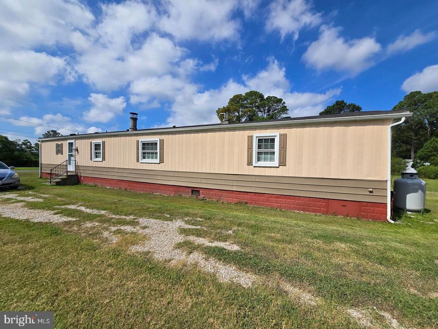 Cute as a button, single wide mobile home located outside city limits of Crisfield with public water and sewer. Home was remodeled in 2015, with house type Thermopane windows and laminate floors throughout. Home is in excellent shape. Open floor plan makes it feel so much bigger. Large living room with wood look exposed beams.  Off the living room is the master bedroom with large walk-in closet and master bath. The kitchen had plenty of room for your dining room table. Off the kitchen is the 2nd bedroom with its full bathroom.  Nice size yard with small deck to sit on.  There is a Large 12'x20' garage/storage building that is big enough to park a car.  Convenient location for shopping and recreational facilities, within walking distance to public beach and fishing pier.  Fireplace is "AS IS", it has never been hooked up by seller.