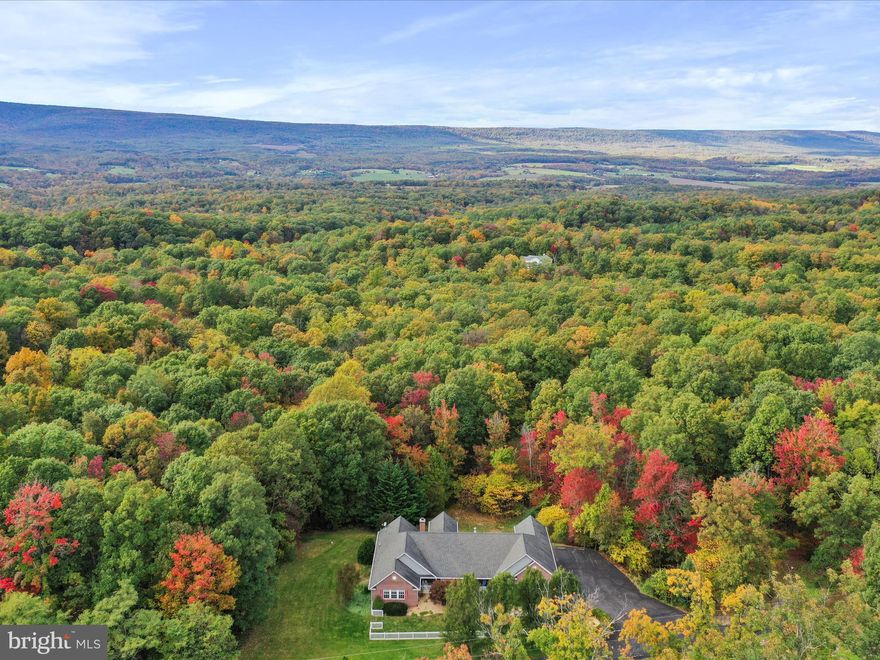 Discover this 3-bedroom, 2-bathroom rancher, beautifully set on 5.3 private acres. With a stylish brick front and a three-car side load garage, this home offers both aesthetic appeal and functional design.  Enter through the gated driveway, featuring a remote opener for added convenience, and be welcomed by a relaxing covered front porch—the perfect spot to unwind. Inside, the home boasts a spacious sunroom with breathtaking views, creating an ideal setting for relaxation or entertaining guests.  The kitchen and a dedicated media room in the basement are finished with luxury vinyl plank flooring, providing durability and a contemporary look. The family room is centered around a cozy wood-burning fireplace, adding warmth and ambiance to this inviting space.  Additional features include a partially finished walkout basement , expansive rear decks and a porch, offering multiple outdoor living options and enhanced connectivity with the natural surroundings.  Recent upgrades ensure this home is move-in ready. The septic system was replaced in 2023, the HVAC system was upgraded in 2022, and a new water treatment system was installed in 2024, providing peace of mind and comfort for years to come.  This property is a true gem, combining ample indoor and outdoor space, modern updates, and a tranquil setting. It's perfectly suited for those seeking a peaceful retreat with the convenience of modern living. Whether you're enjoying the scenic views from the sunroom, relaxing by the fireplace, or exploring the vast grounds, this home offers a unique lifestyle opportunity in a serene and private setting.