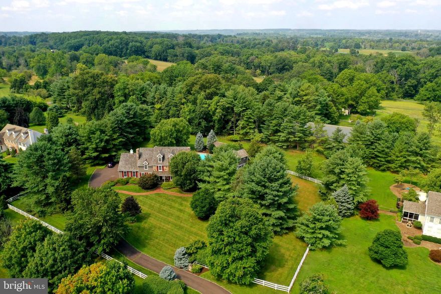 Located in one of the most beautiful & desirable communities in Solebury, Laurel Ridge is an enclave of exquisite homes uniquely positioned for ultimate & preferred privacy. Follow tree lined country roads, lush farm fields & mature penns woods forests to this exquisite & delightful home. The meticulously manicured lawn with over 2 acres of  perrenial gardens, decidous trees & conifers all work in unison to create a dynamic landscape to showcase this spectacular house.
Turn down a winding driveway to a meandering brick walkway which delivers you to a charming covered front porch. Once inside the magic continues with extensive  millwork,  old world craftsmanship, light filled spaces & an incredibly easy flow from room to room. The kitchen has granite countertops, huge center island, beautiful cabinetry and designated dining space. It is open to the family room with floor to ceiling stone fireplace as a focal point, back staircase & french doors to access the multi-tiered deck and pool area bursting with glorius gardens & step down patio, perfect for entertaining.  There is a mudroom off the kitchen with access to the oversized  3 car garage, The mudroom has built-ins & cubbies for storage. A handsome den boasts a  fabulous mercer tile fireplace and a wall of built-in shelves & cabinets. The formal dining room & living room complete the main area of the first floor. Extraordinary millwork, deep sill windows and an elegant fireplace are just a few of the rich attributes of these public rooms. Follow a turned staircase to the second floor center hall. This floor offers a master bedroom with fireplace, masterbath with custom  wrap around seating area, walk in closet with laundry area. There are 3 more graciously sized bedrooms and two full bathrooms on this level. The third floor has large windows, beadbaord, built in shelves, closets, and alcoves to create a charming and delightful space. There is a built- in office area & full bathroom. Back to the first floor and the stunning addition, A collaboration of local renowned architect Lynn Taylor & premier builder J R Maxwell. There is a seamless & natural flow from the main house into the impressive addition with spacious great room with radiant heat, high ceilings and window wall overlooking the pool area & gardens. Making this room yet another perfect gathering space. The addition has everything necessary for a full guest quarters, aupair or in-law suite. With exquisite millwork, hardwood floors, and lovely open staircase, it blends with the character & charm of the main house. The other rooms include a living room, kitchen, bedroom & 3 beautiful full baths with stall showers. There are exterior entrances in both the front hall of the addition and in the rear with access from the pool to a full bathroom and kitchen. Adding to the expansive designated public rooms, there are rooms for multiple family members to comfortably work from home. Including a large open bonus room with built-in cabinets and shelves & 2 smaller rooms for a possible home gym & game room. These areas would also be perfect for a  combination game room, theatre & wine cellar. The possibilities are endless with the room to create your dream entertainment space. Located close to popular orchards, farmers markets, galleries & shops, this is a once in a lifetime opportunity for those looking for a grand & magnificent home all within the award winning  New Hope Solebury School District. The farm behind the property is Conserved along with many others on Laurel & Comfort Roads.