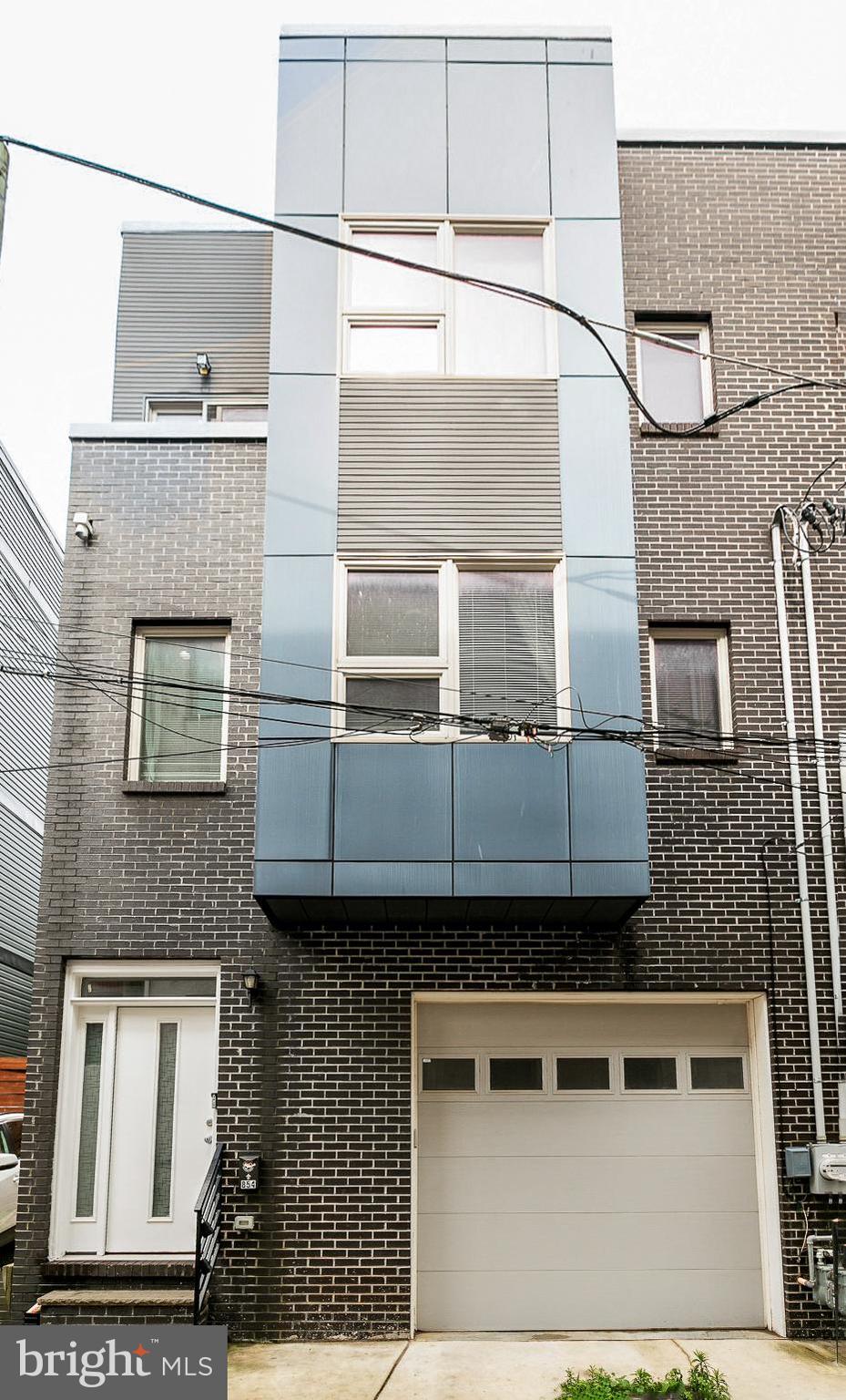 Hidden away on a quiet, cobblestone alley in the heart of Philly's vibrant Northern Liberties neighborhood, you'll discover 856 N Leithgow St. This modern 3-story home offers 3 bedroom suites with 4.5 total bathrooms, a finished basement, a private patio, a roof deck, and a sought-after 1-car garage. A towering brick facade greets you out front. Inside, you're welcomed by a foyer with access to the garage. Gleaming hardwood floors stretch down the hall into a large, sunlit bedroom suite with an attached full bathroom, a walk-in closet, and French doors that can be left open as an additional living space or closed for a private office. A pair of sliding doors open to the secluded rear patio, perfect for hosting barbecues or relaxing alone. The finished basement provides another bonus space, ideal for a gym, playroom, or home theater, along with a full bathroom, laundry, and storage. Upstairs, the huge, open main level is bright and airy, with lots of natural light pouring in. There's tons of space to hang out in the living room at the front. The kitchen and dining area has white shaker cabinetry, natural stone counters, stainless steel appliances, a tile backsplash, an island with seating, a pantry, a half bathroom, and a Juliet balcony. The home's third floor has a large primary suite with lots of bright windows, a walk-in closet, and a luxurious attached bathroom featuring a double vanity, a glass-enclosed shower, and sleek tile. A second bedroom suite with a full bathroom completes the level. A final staircase with a terrace at its base leads to the expansive roof deck that's sure to be a popular place to enjoy time with family and friends while admiring the skyline views. 856 N Leithgow St's fantastic location earns a Walk Score of 88! The tax abatement started in 2017. Top-rated restaurants, friendly shops, and lively entertainment fill the surrounding blocks. Playful parks are close, and neighboring Fishtown has lots more to explore. There's also easy access to I-676, I-95, and South Jersey. Schedule your showing today!