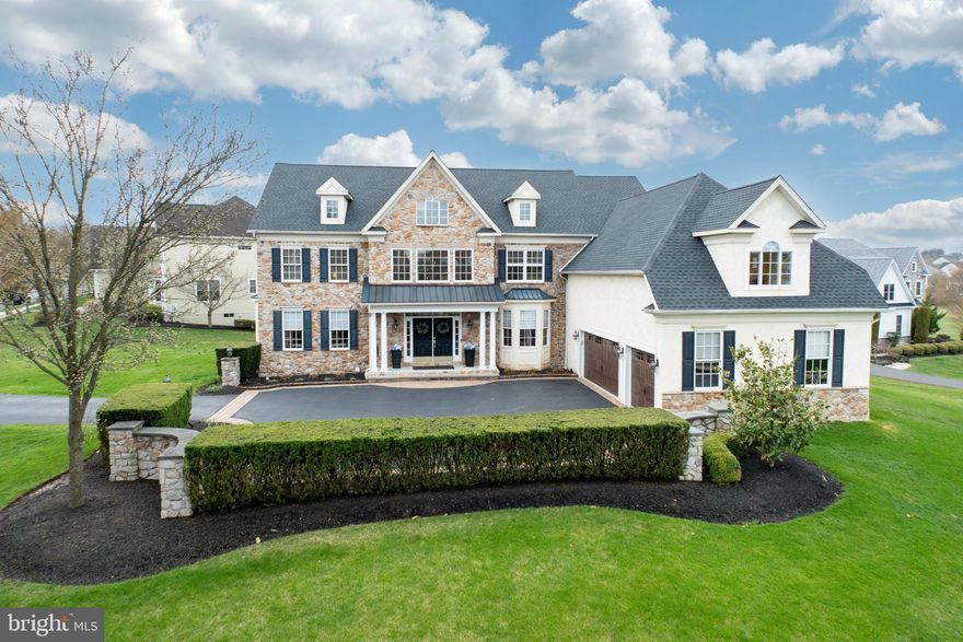 This stately stone-front Colonial is gracefully positioned on a premium corner lot within the prestigious Lederach Golf Club community, adjoining the scenic public course. With a west-facing rear orientation, the home captures breathtaking sunsets and views, best enjoyed from the newly constructed Timber Tech deck, featuring a sleek vertical cable railing system that perfectly complements the picturesque surroundings. The outdoor living experience continues with a beautifully designed circular paver patio, complete with a custom stone half wall and built-in wood-burning fire pit-an ideal setting for entertaining or relaxing beneath the stars. The front courtyard, framed by stone walls and manicured hedges, enhances the home’s sophisticated curb appeal. Inside, a 2 story foyer with wood flooring, elegant chandelier, and a split double staircase makes a lasting impression. The formal dining room, to the right, offers refined character with a tray ceiling, bay window, new wainscoting, and a striking custom accent wall. To the left, the living room features a tray ceiling and bay window and flows into a butler’s pantry with rich cherry cabinetry, ideal for effortless entertaining. A bright, inviting home office with wood floors and a bay window offers a quiet and inspiring place to work. Also on the main level are a stylish powder room, a mud room and a spacious laundry room. The heart of the home is the expansive eat-in kitchen, designed for both function and style. An oversized center island with pendant lighting serves as a gathering place, while tile flooring and backsplash, a walk-in pantry, built-in desk area, and newer stainless-steel appliances make everyday living and entertaining a pleasure. New Marvin sliding glass doors open seamlessly to the elevated deck and patio below, extending your living space outdoors. Just beyond, the two-story family room stuns with a dramatic wall of windows and a gas fireplace, creating a warm and welcoming atmosphere. Upstairs, the luxurious primary suite is a serene retreat, complete with a cozy sitting area enhanced by custom built-in bookshelves and a gas fireplace, as well as a tray ceiling that adds architectural interest. The suite also offers three walk-in closets, a separate vanity space, and a spa-inspired en-suite bath with his-and-her vanities, a soaking tub, and a large walk-in shower. Each of the three additional bedrooms includes its own en-suite bath, providing comfort and privacy for guests or family members. One of these bathrooms is enhanced by a skylight. The fourth bedroom is currently utilized as a craft room, featuring a full wall of built-in shelving-ideal for creative pursuits, or conversion to a second office. The walkout lower level continues the home’s theme of spacious luxury, with 9-foot ceilings and full-size windows creating a bright and open environment. This finished space includes a generous family room, a full bath, and a private den currently styled as a "man cave," complete with a dedicated ventilation system and custom double ceiling- making it a perfect media room, lounge, or even a cigar retreat. A large unfinished area remains, offering excellent storage or future finishing potential.  With over $185,000 in recent upgrades—including two new HVAC systems, premium hardscaping and landscape lighting, updated paint, lighting and plumbing fixtures, Elite Wi-Fi-enabled garage doors, new carpeting in the family room, and more. Ideally located just minutes from the vibrant shops and dining of Skippack Village, scenic Evansburg State Park, beloved Merrymead Farm, and the Providence Town Center in Collegeville, this home offers a lifestyle of luxury and convenience. Commuters will appreciate easy access to the PA Turnpike, just 10 minutes away. With no HOA fees and a beautifully maintained neighborhood, this exceptional home offers the perfect blend of elegance, comfort, and prime location.